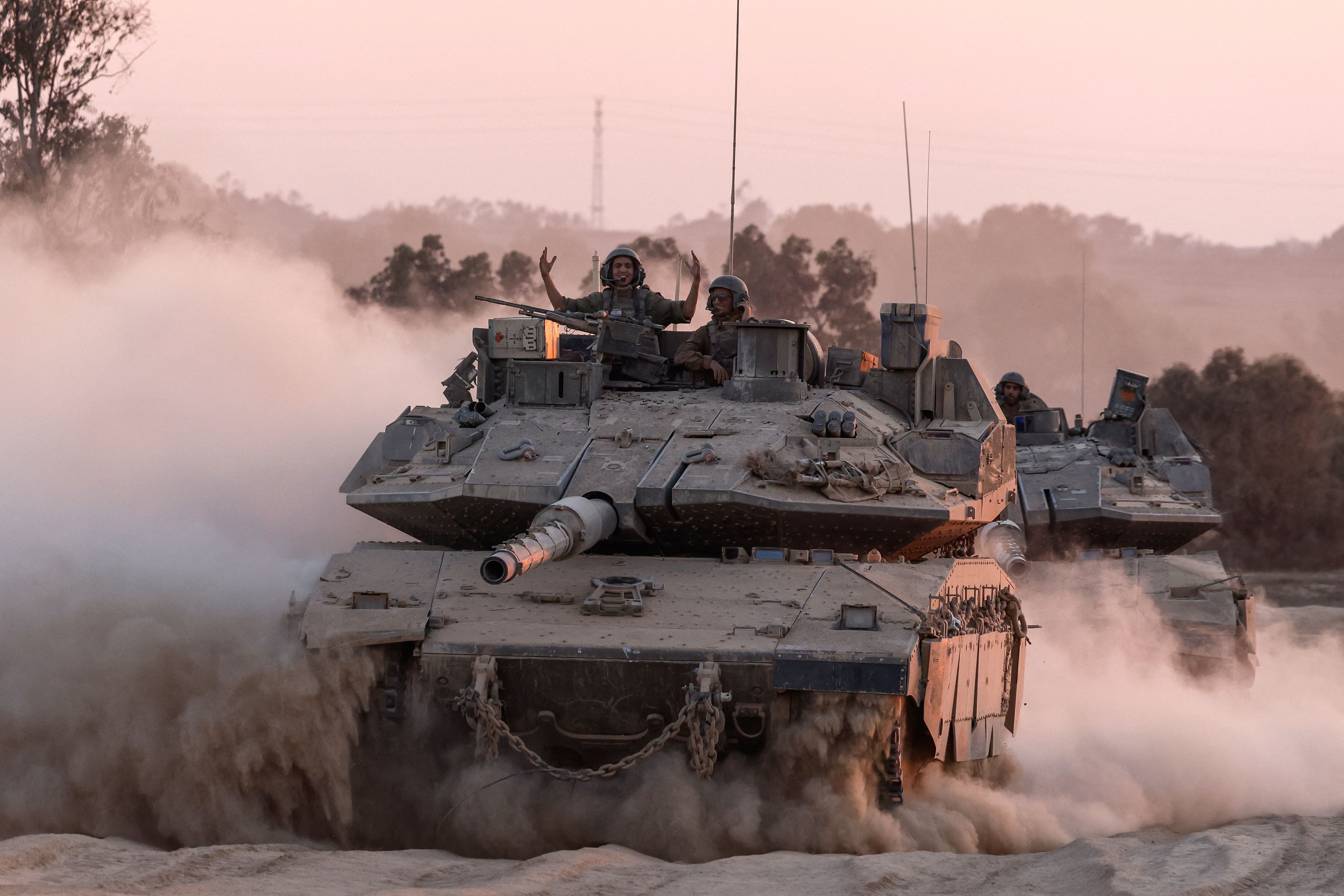 An Israeli soldier gestures on a top of a tank, near the Israel-Gaza border