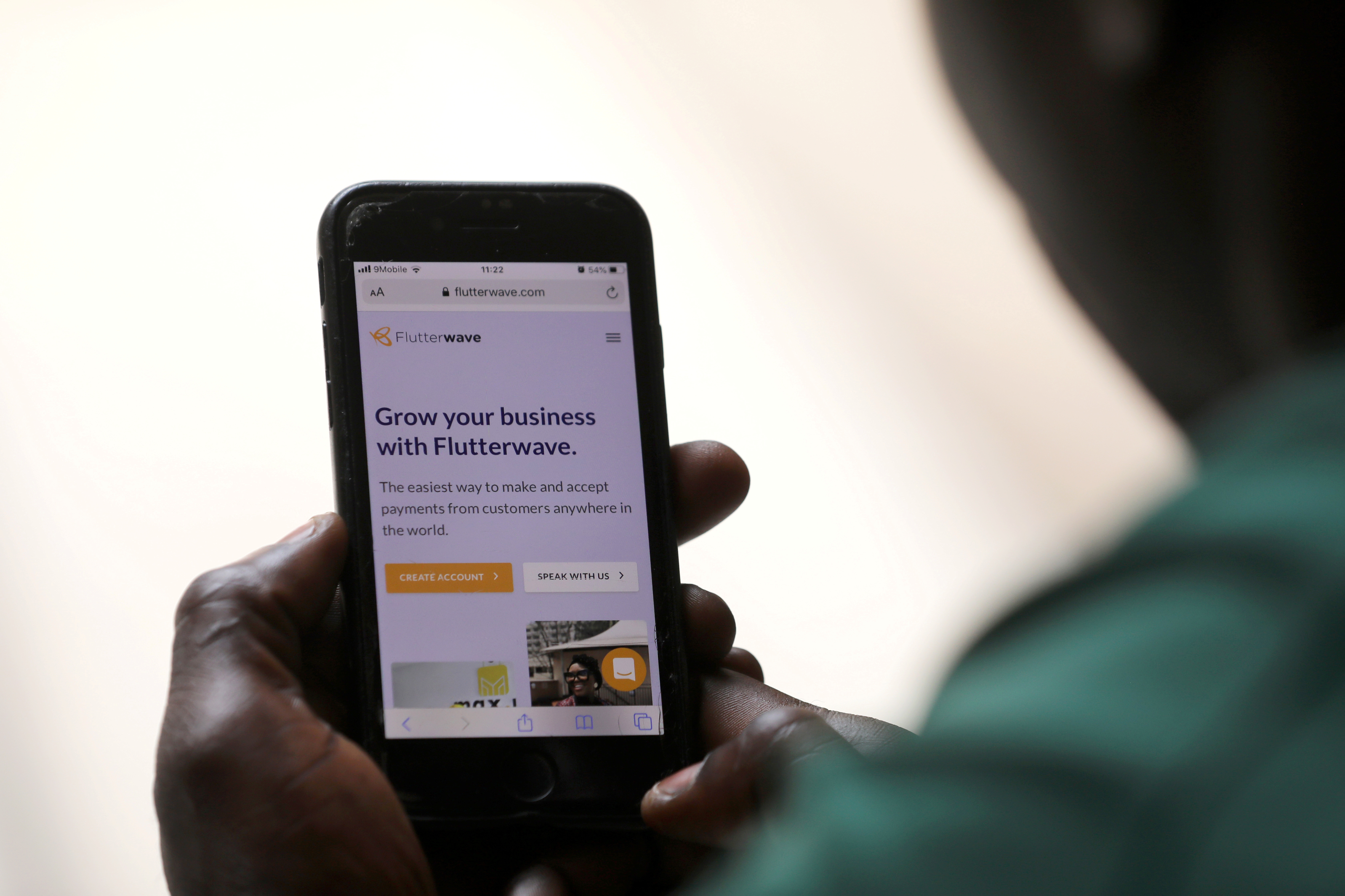 Man poses as he displays Flutterwave homepage on mobile phone screen in Abuja