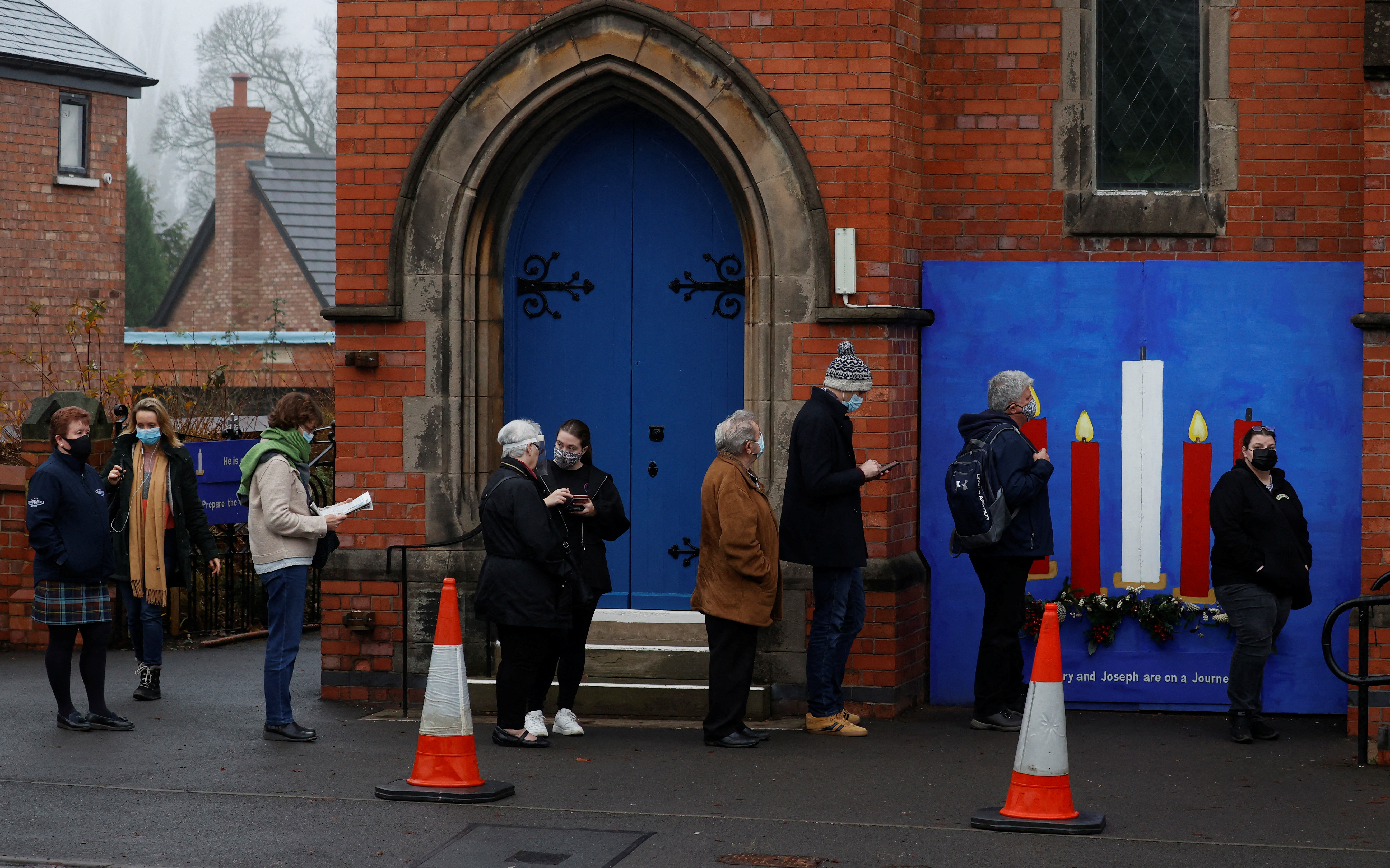 People queue for their booster vaccines outside a coronavirus vaccination centre near Northwich