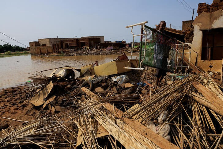 A man collects his belongings after sustaining water damage to his house during floods in Jazeera State