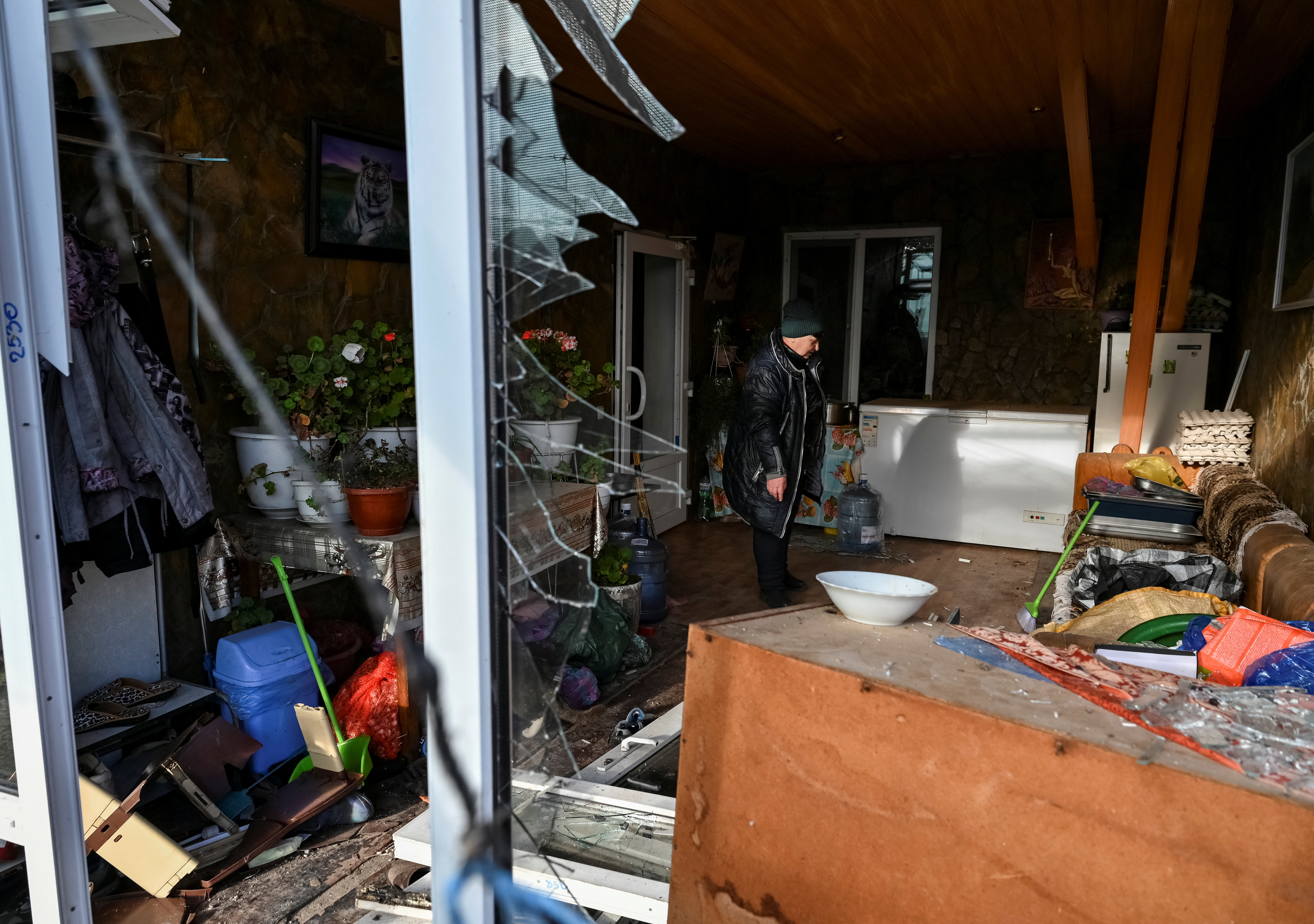 A local is seen in a window her house destroyed by a Russian military strike in the village of Stepne, in Zaporizhzhia Region