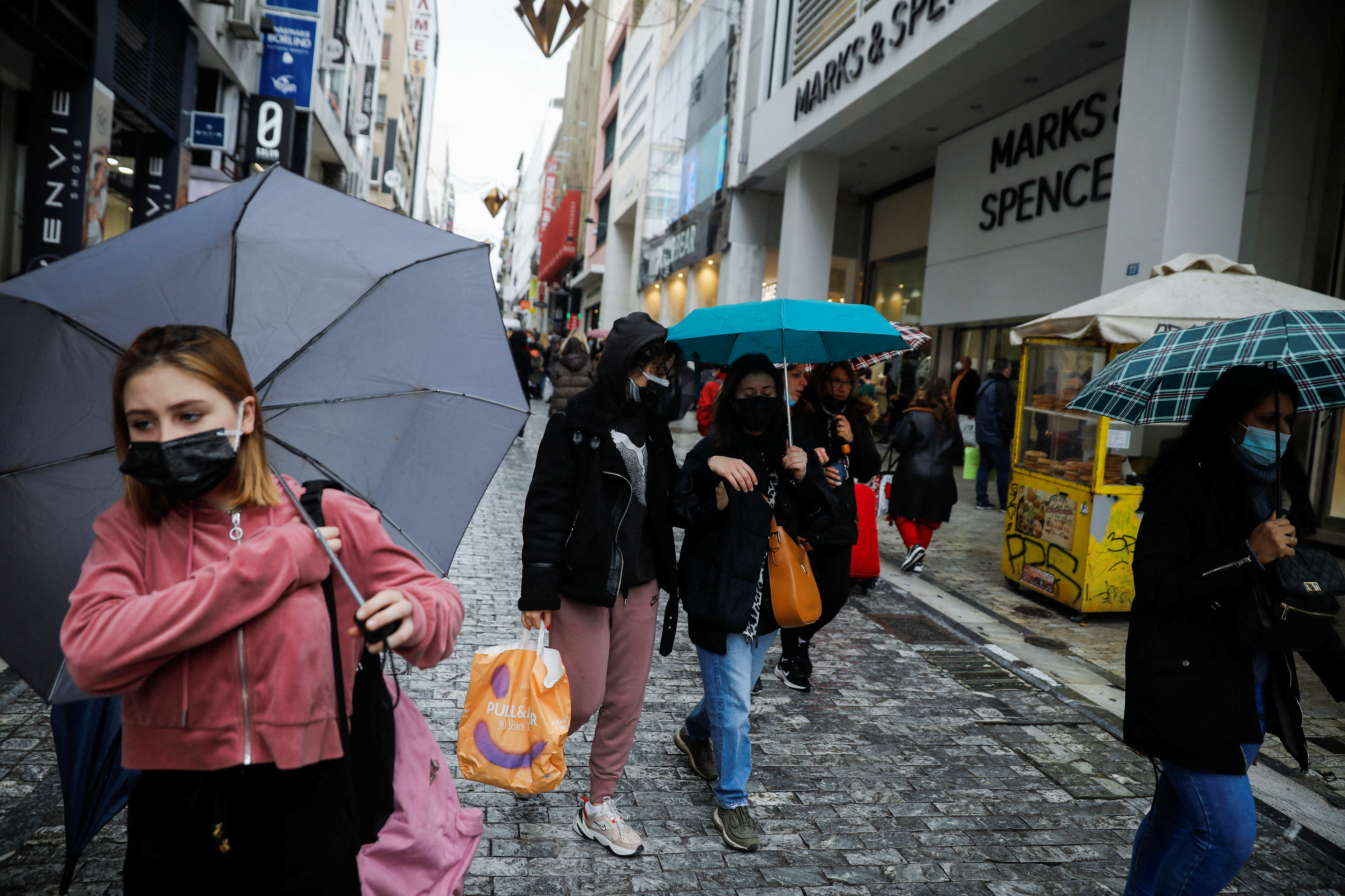People wearing protective face masks walk on the main Ermou commercial street amid the coronavirus disease (COVID-19) outbreak in Athens