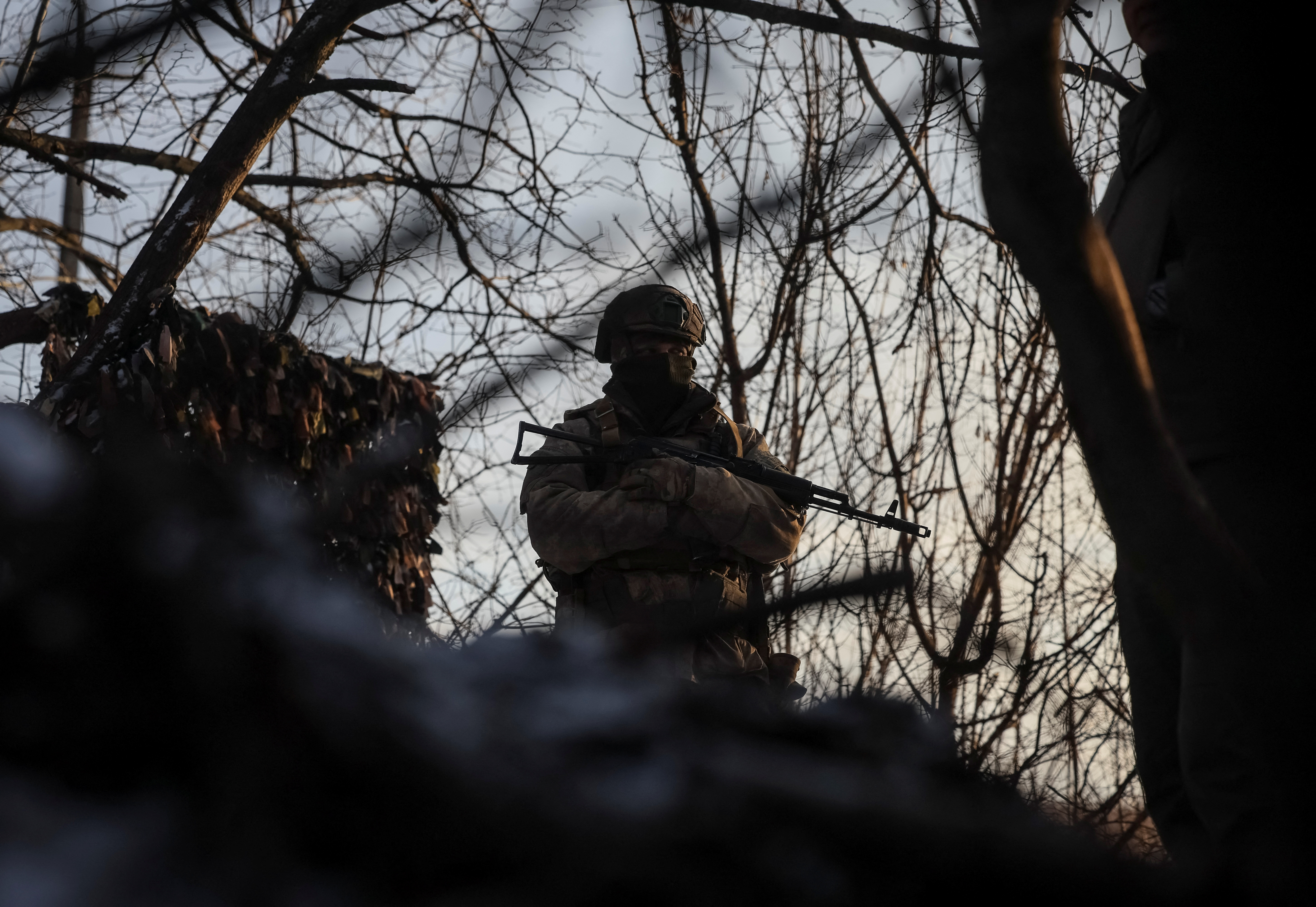 Ukrainian serviceman stands guard at his position in a trench at a front line on the border with Russia in Sumy region