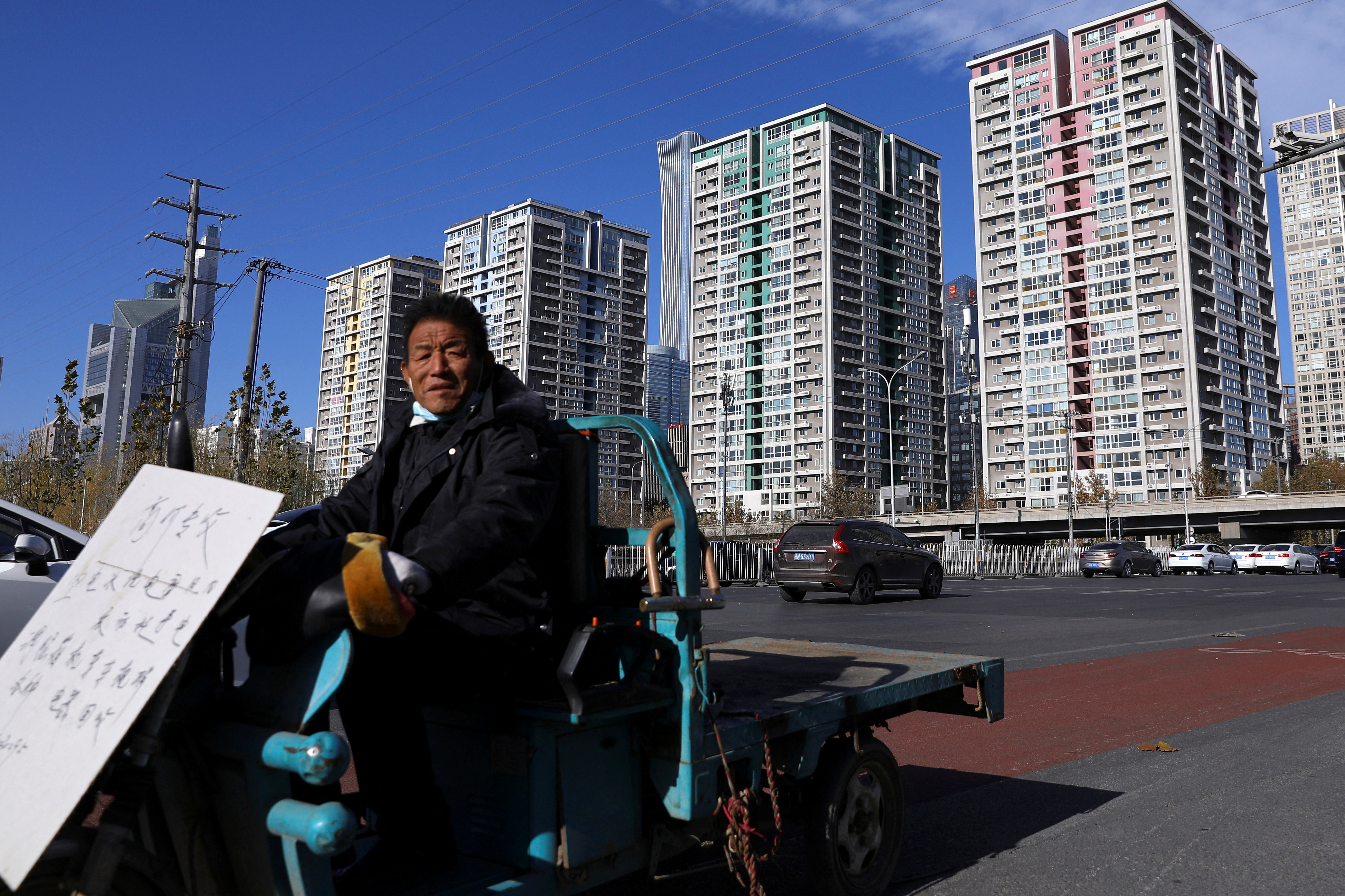 Worker for recycling electric equipment rides past residential buildings in Beijing