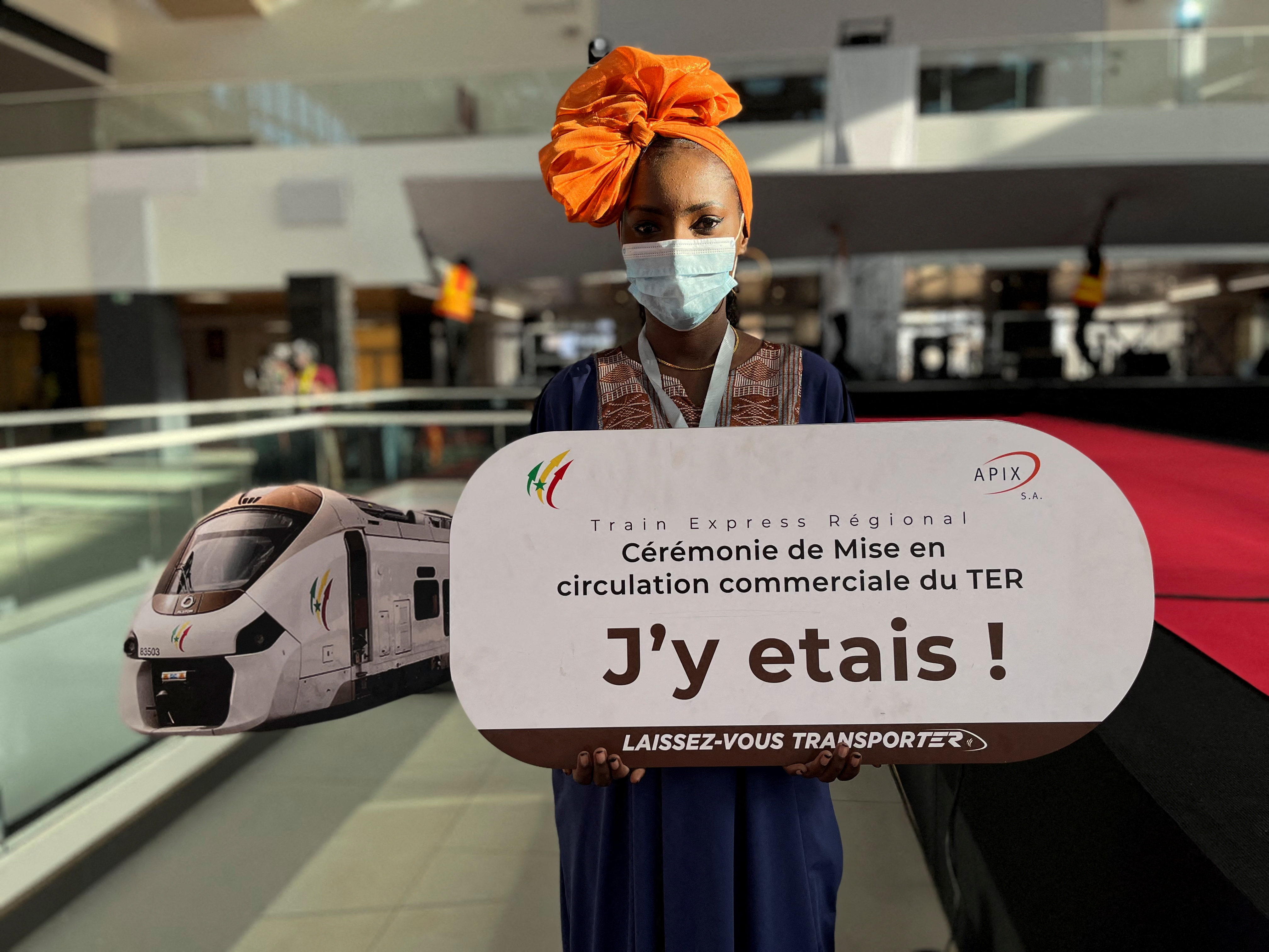 A hostess holds a sign at Senegal's new commuter train station during the launch ceremony of the Regional Express in Dakar, Senegal, December 27, 2021. The sign reads: "TER commercial circulation launch ceremony. I was there! Let yourself be transported". REUTERS/Elodie Toto