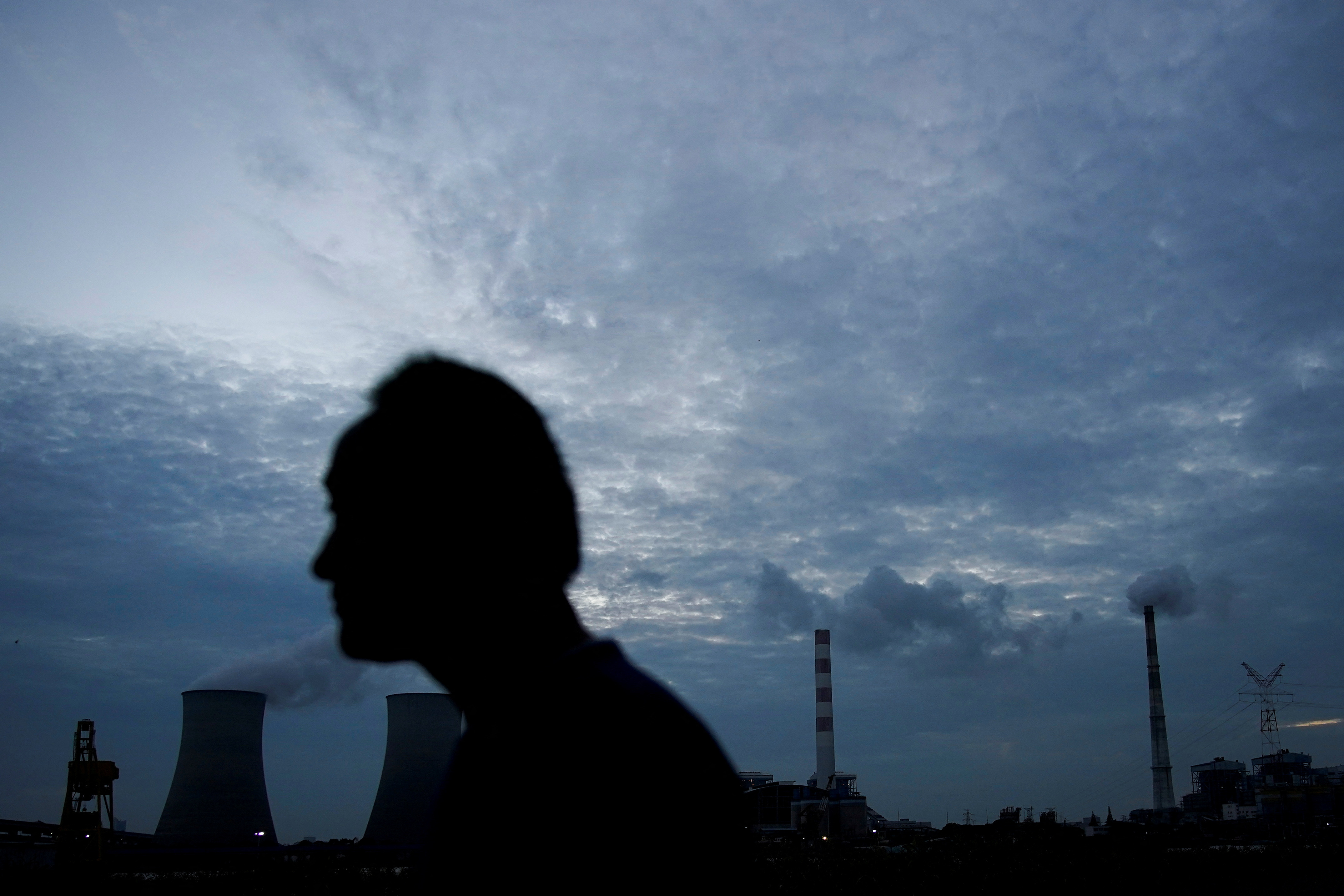 A man walks past a coal-fired power plant in Shanghai