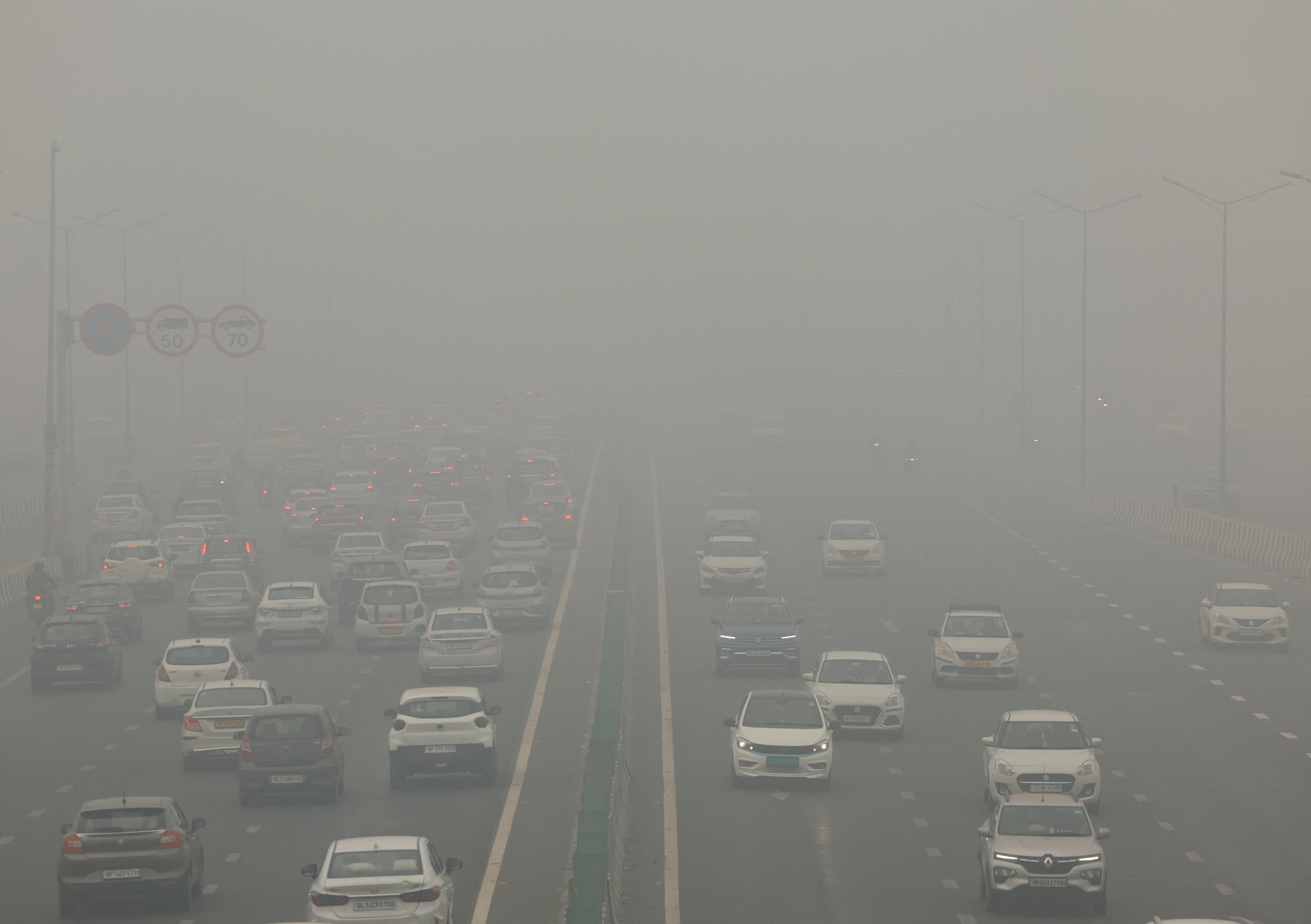 Traffic passes on a road as the sky is enveloped with smog after Delhi's air quality turned "severe" due to alarming air pollution, in New Delhi