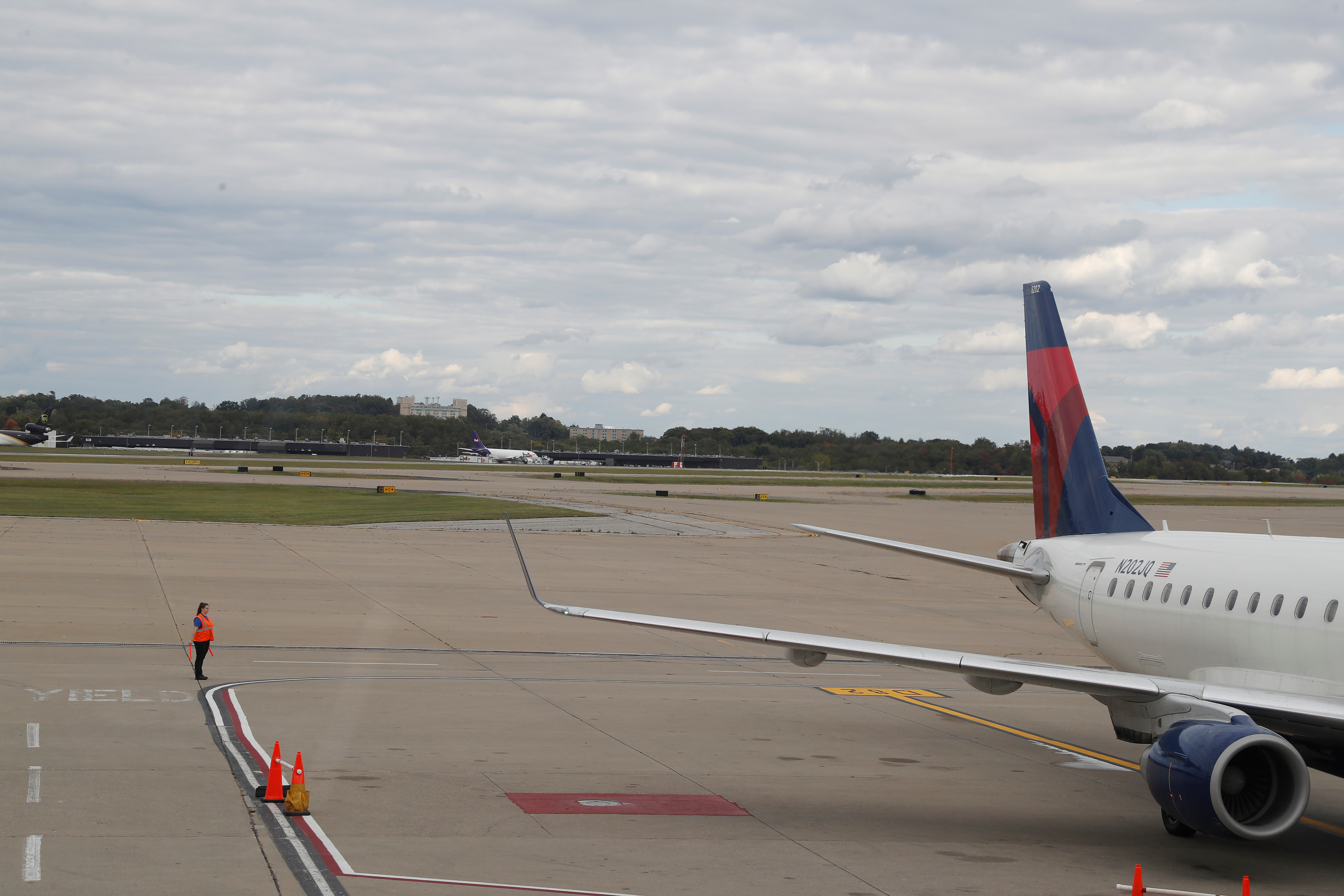 An airport worker stands on a tarmac next to a Delta Air Lines plane at Pittsburgh International Airport in Pittsburgh, Pennsylvania