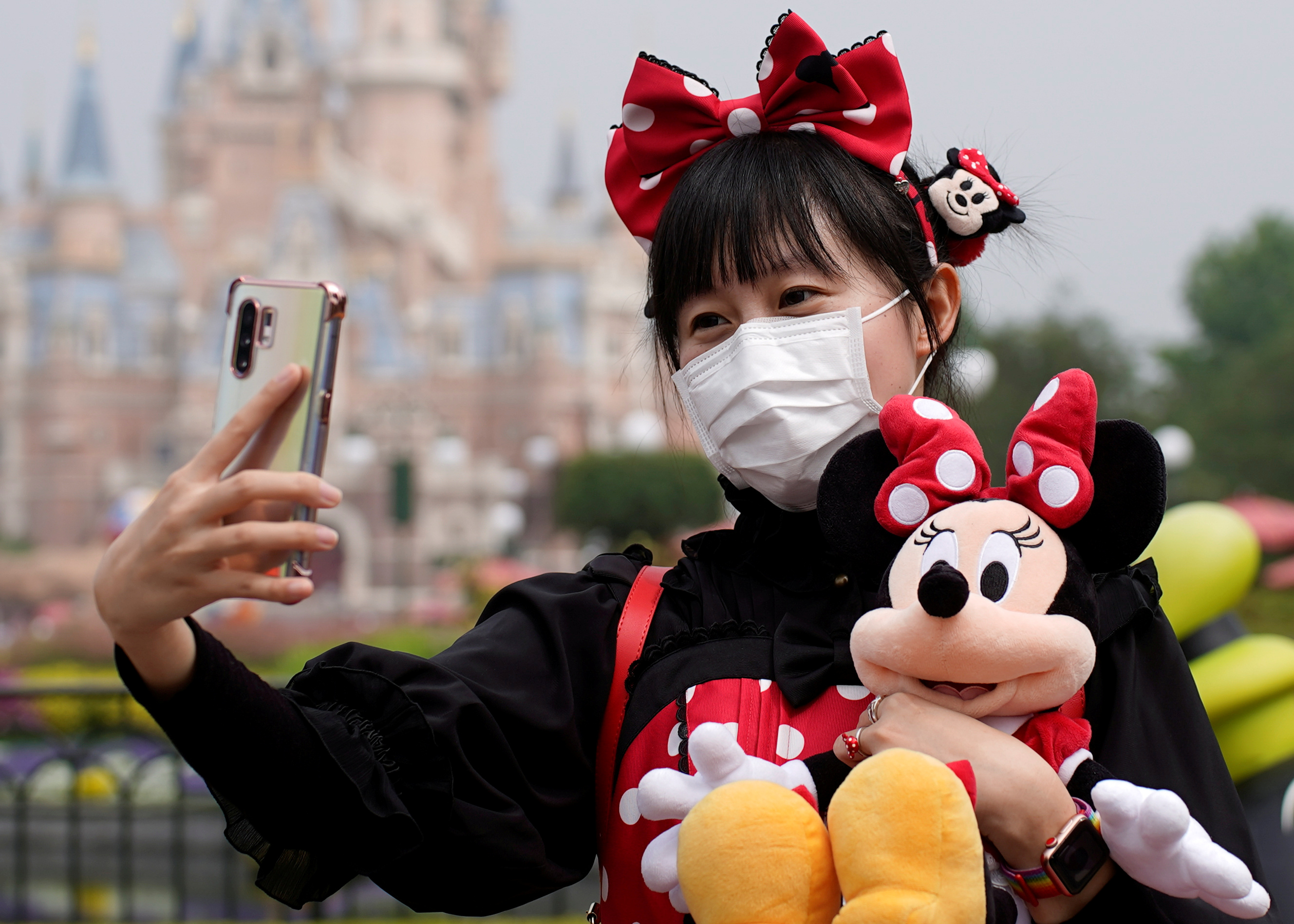 A visitor dressed as a Disney character takes a selfie while wearing a protective face mask at Shanghai Disney Resort as the Shanghai Disneyland theme park reopens following a shutdown due to the coronavirus disease (COVID-19) outbreak, in Shan