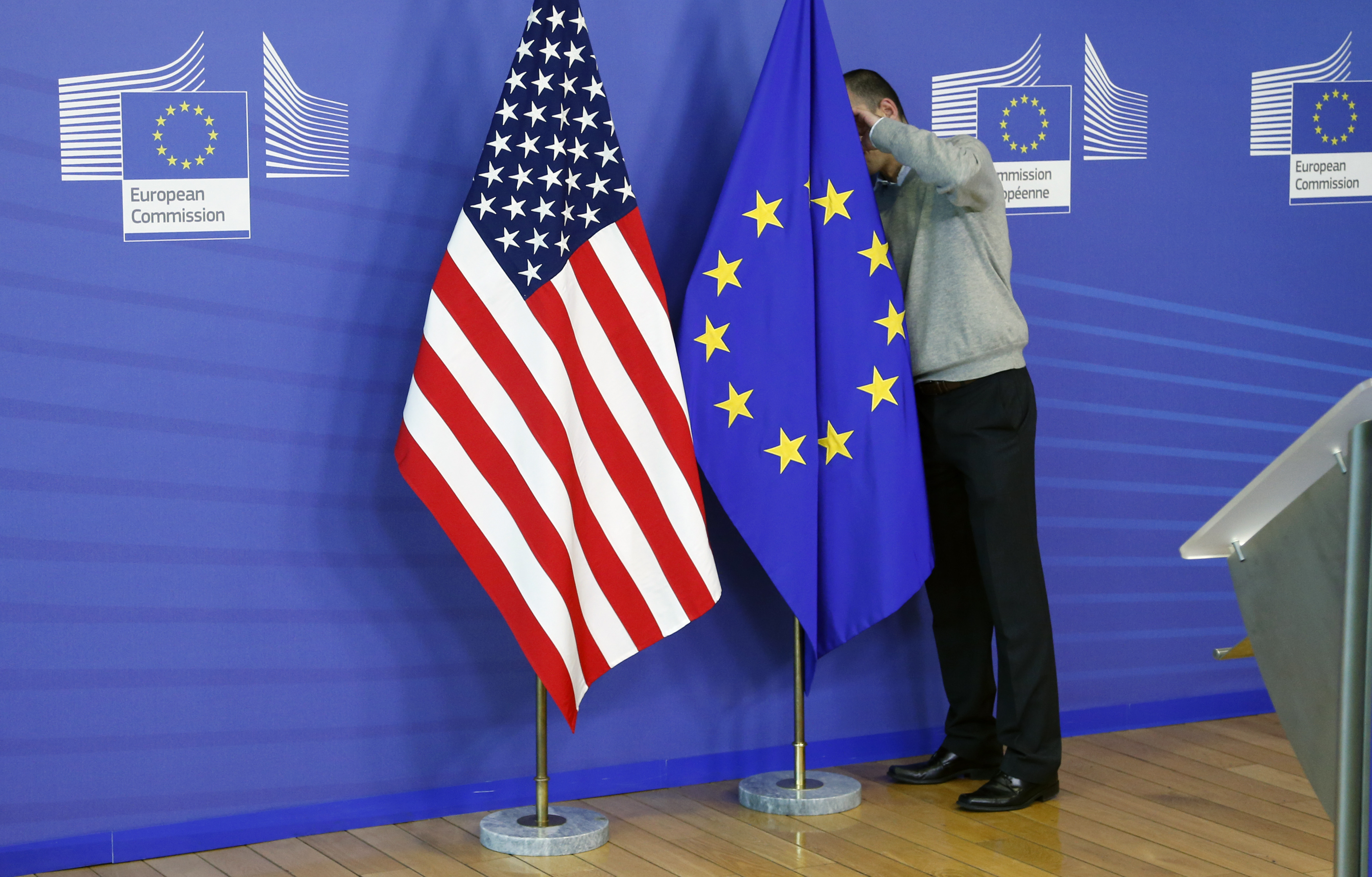 A worker adjusts EU and U.S. flags at the start of the 2nd round of EU-US trade negociations at the EU Commission headquarters in Brussels