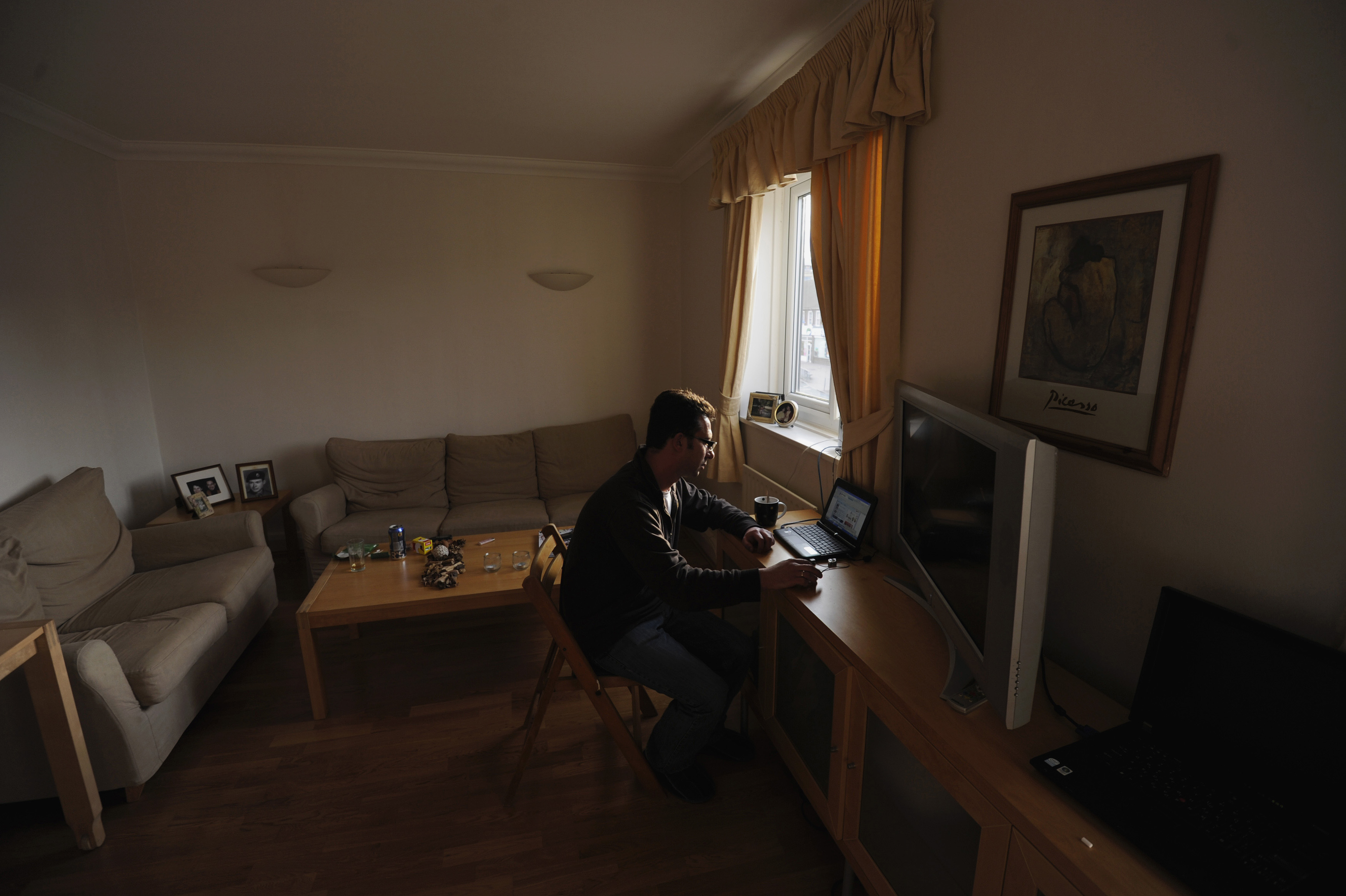 George Kapetanios looks at a laptop computer at his flat in Potters Bar, on the outskirts of London