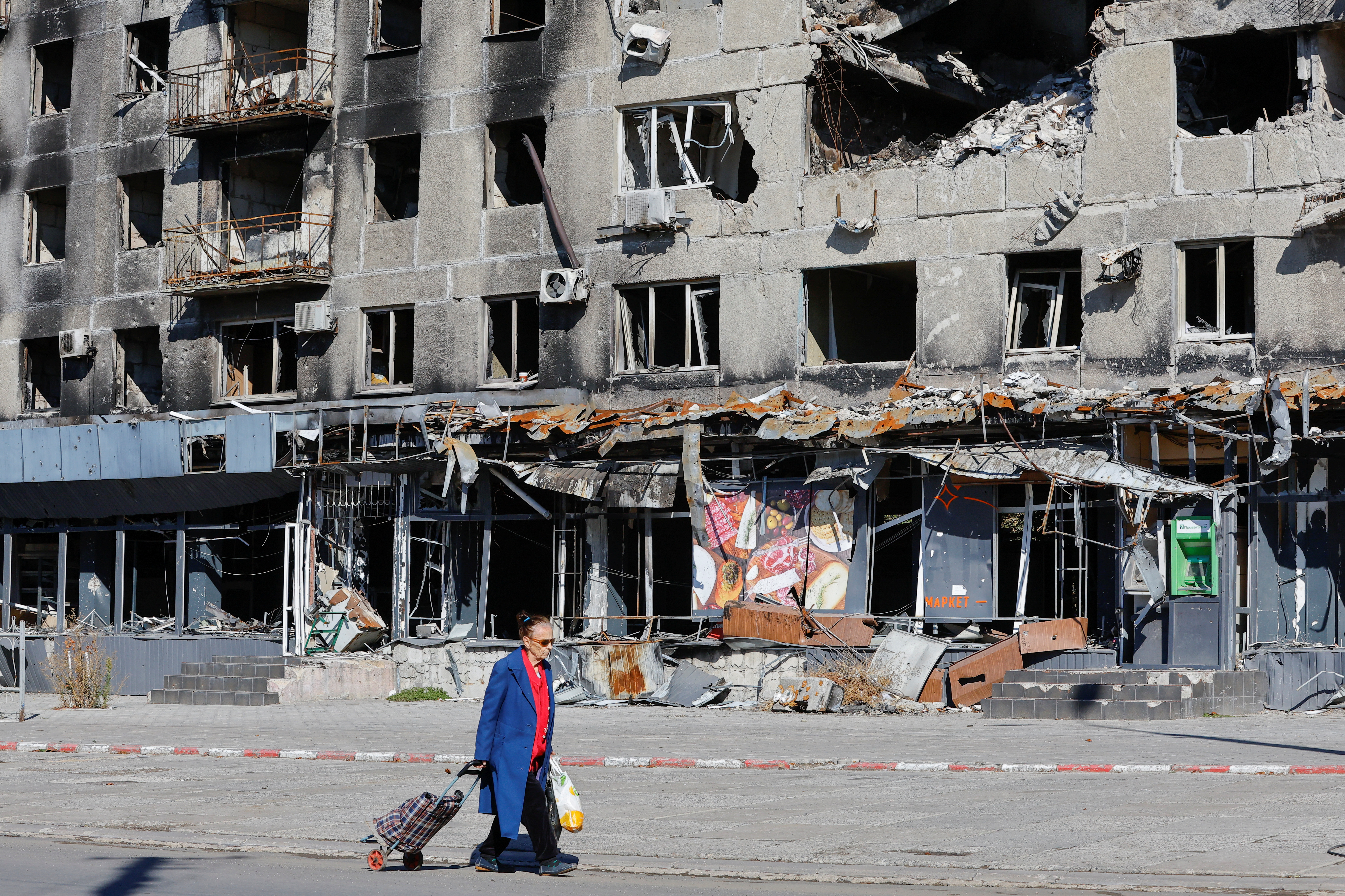 Un residente local pasa junto a un bloque de apartamentos dañado en Mariupol.
