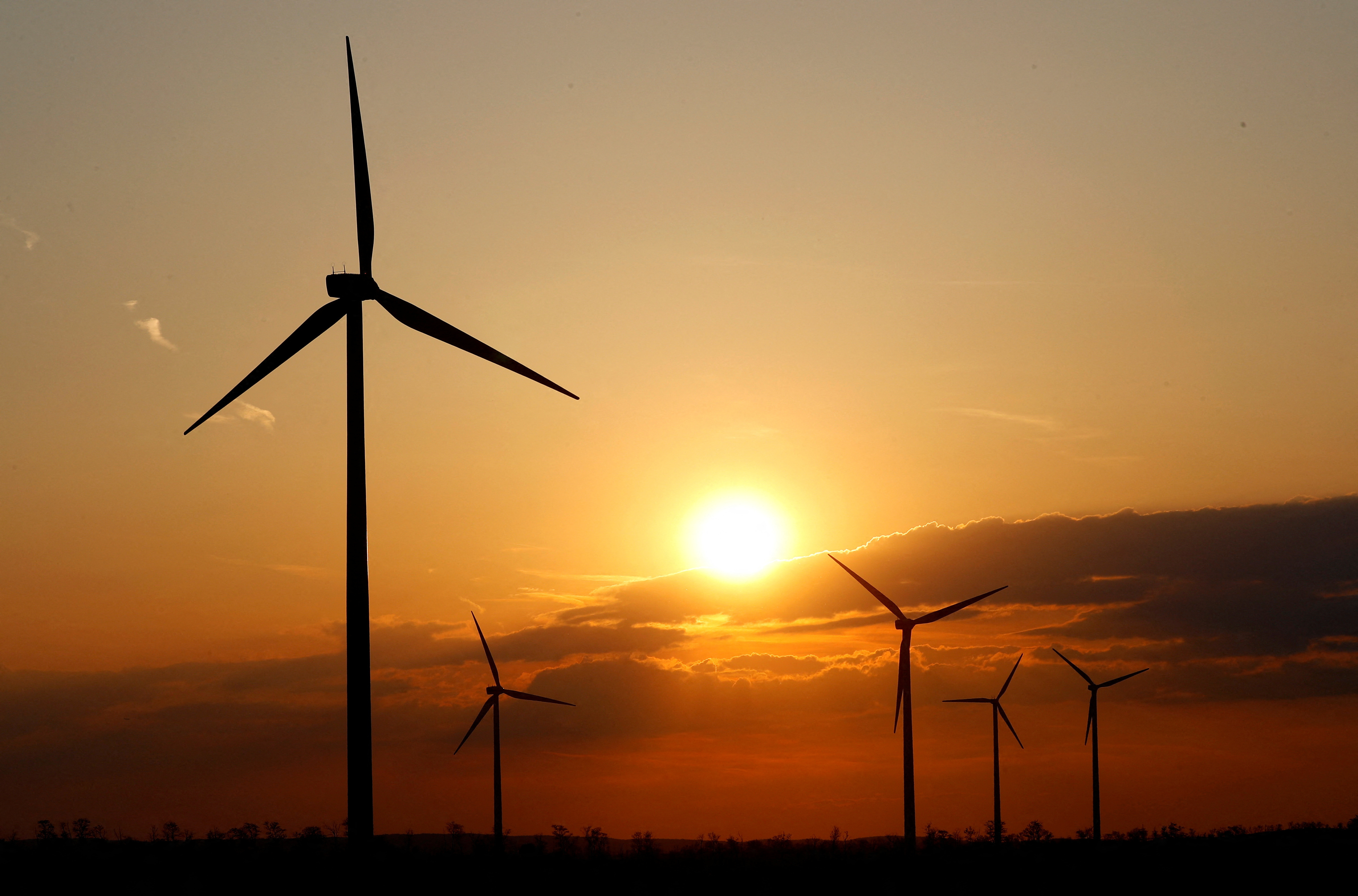 Power-generating windmill turbines are seen during the sunset at a wind park near Moenchhof