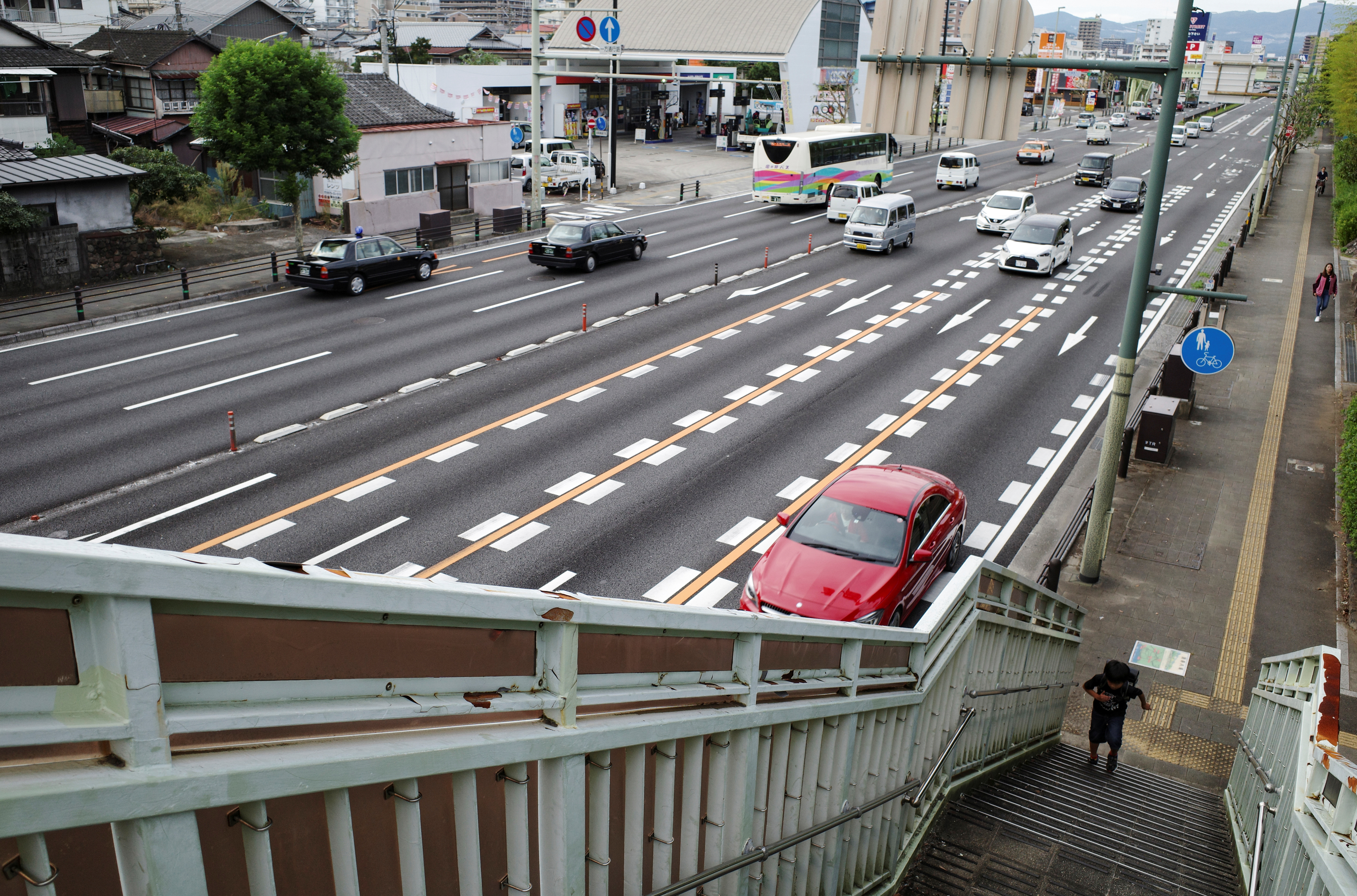  A schoolboy walks up the overhead bridge along a traffic junction in Beppu