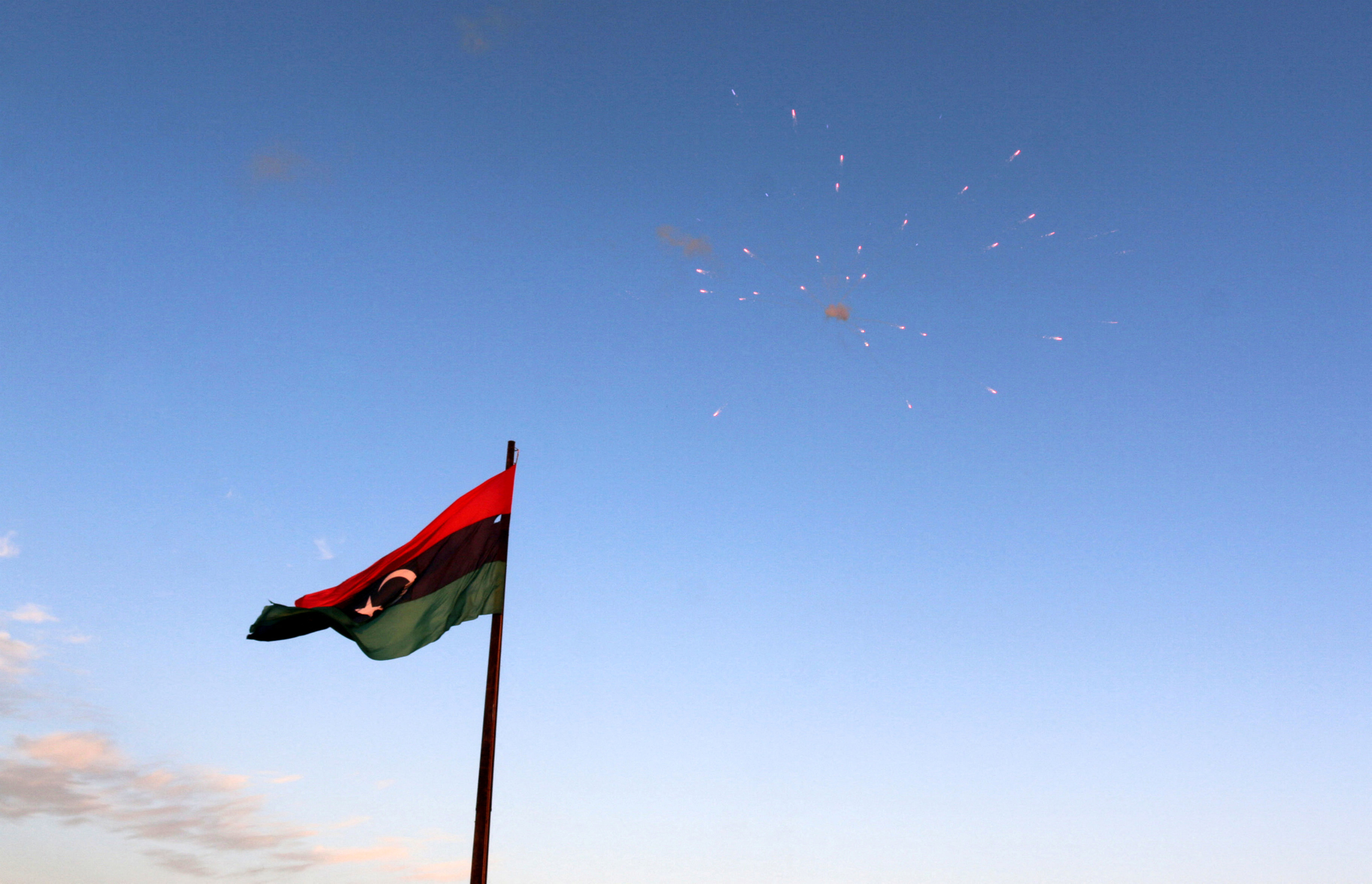 Libyan flag flies as fireworks explode during celebrations after Libyan forces allied with the U.N.-backed government finished clearing Ghiza Bahriya, the final district of the former Islamic State stronghold of Sirte