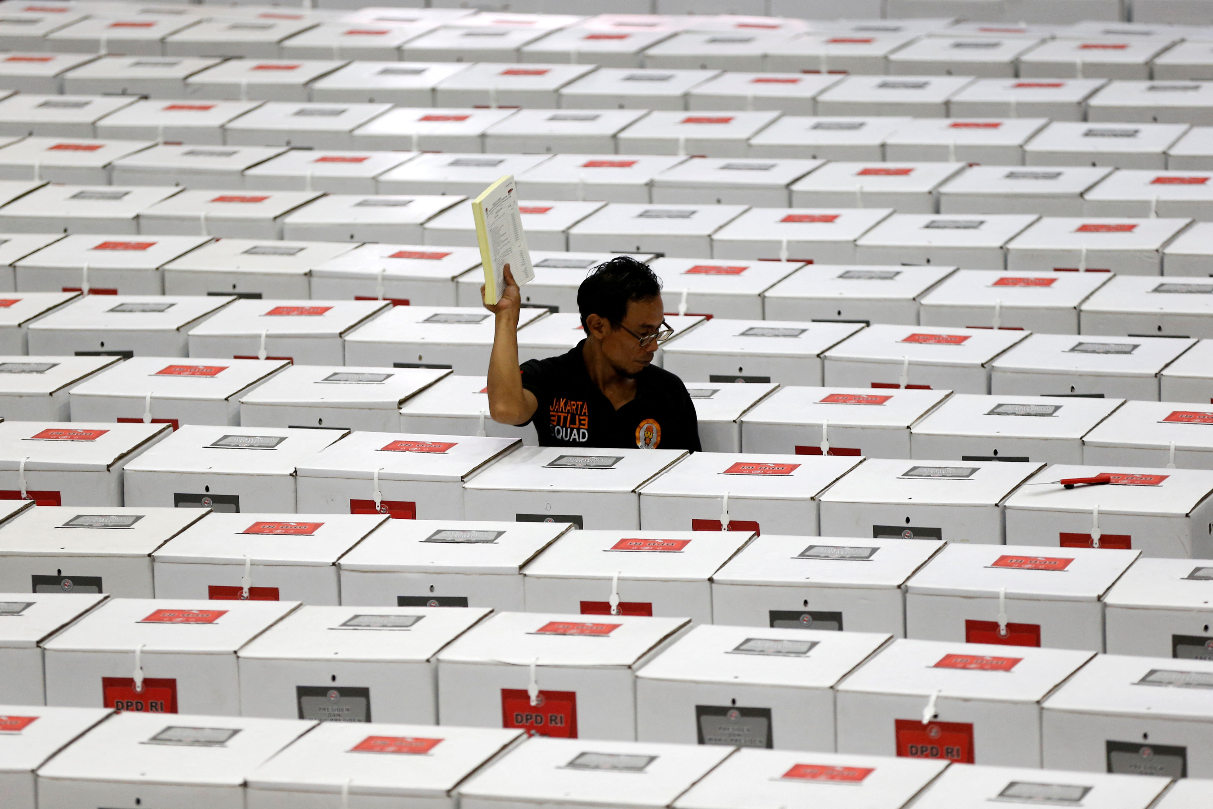 A worker carries election materials as he prepares ballot boxes in a warehouse in Jakarta