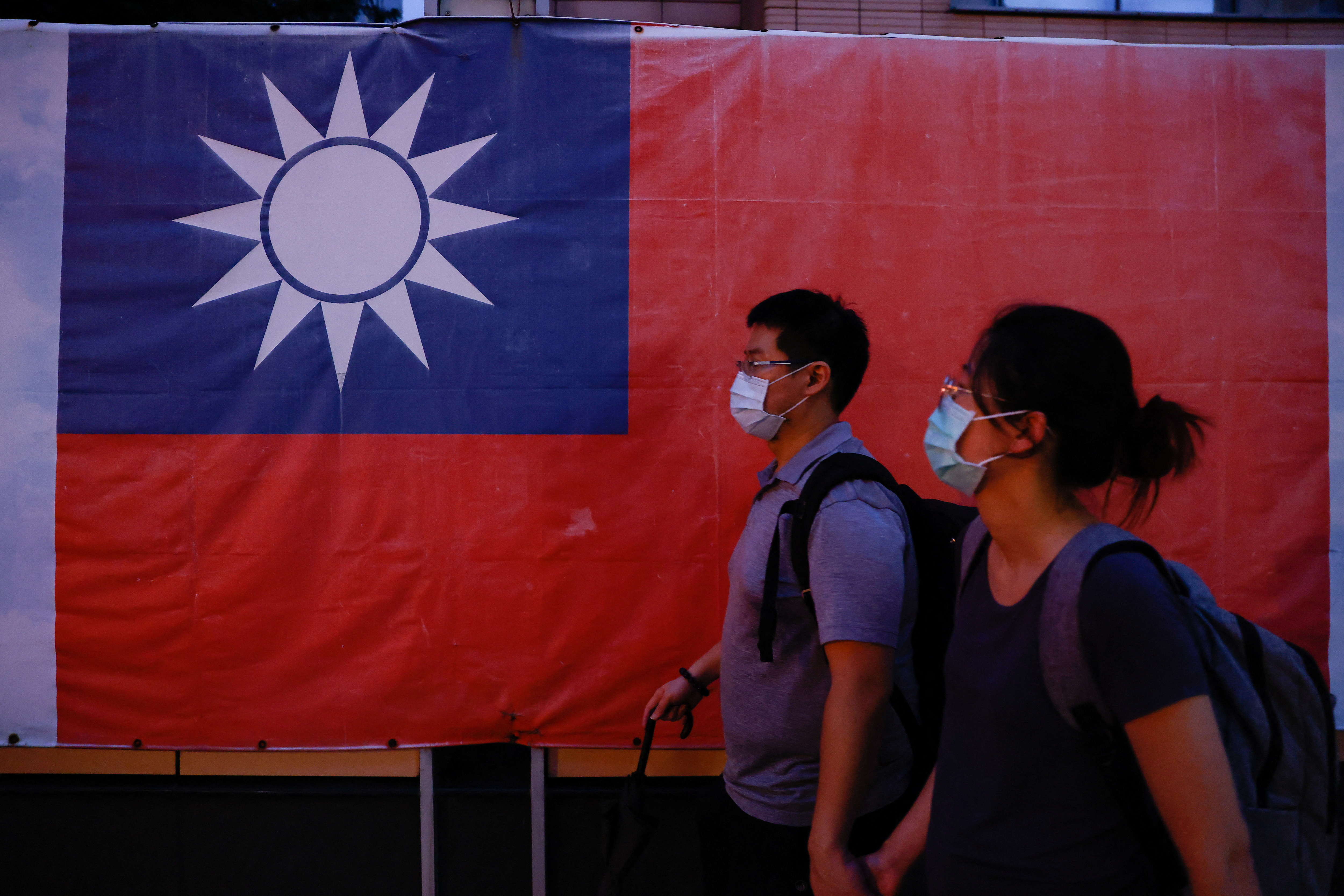 People walk past a Taiwan flag in Taipei