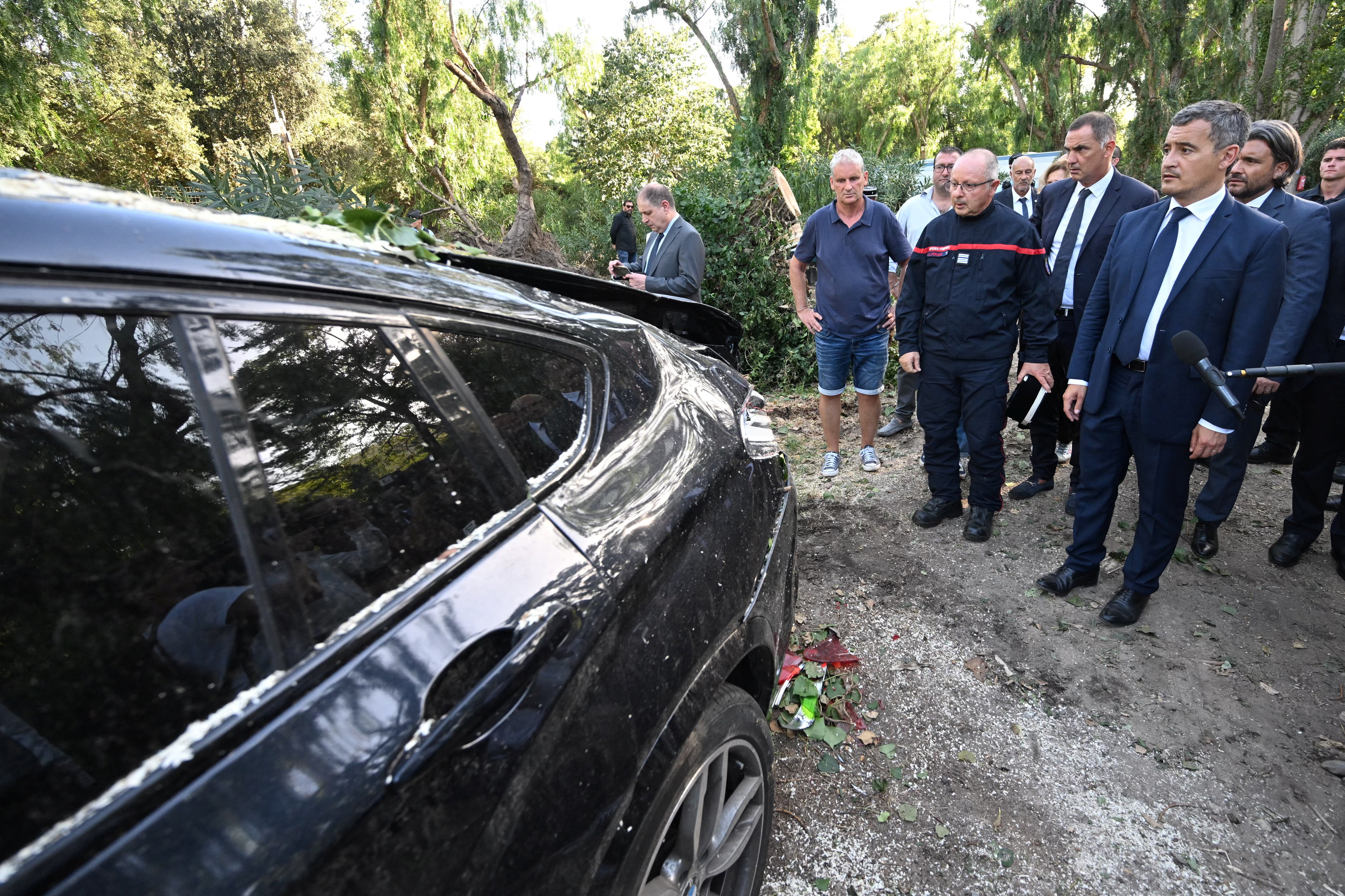 France's Interior Minister Gerald Darmanin stands by a damaged car as he visits the Sagone camping site in Sagone