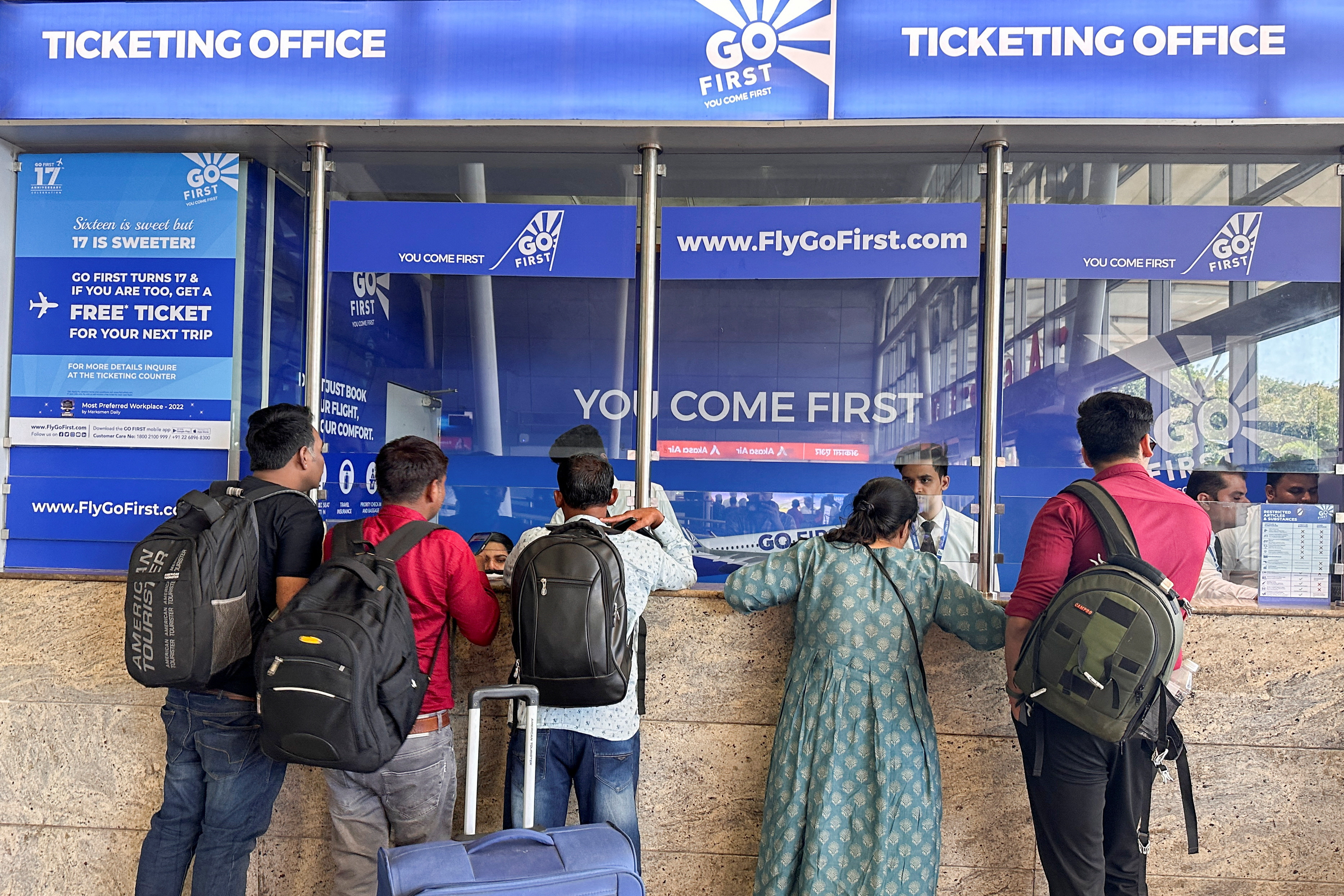 People wait to claim refunds after their flights were cancelled, from the Go First airline ticketing counter at the Chhatrapati Shivaji International Airport in Mumbai