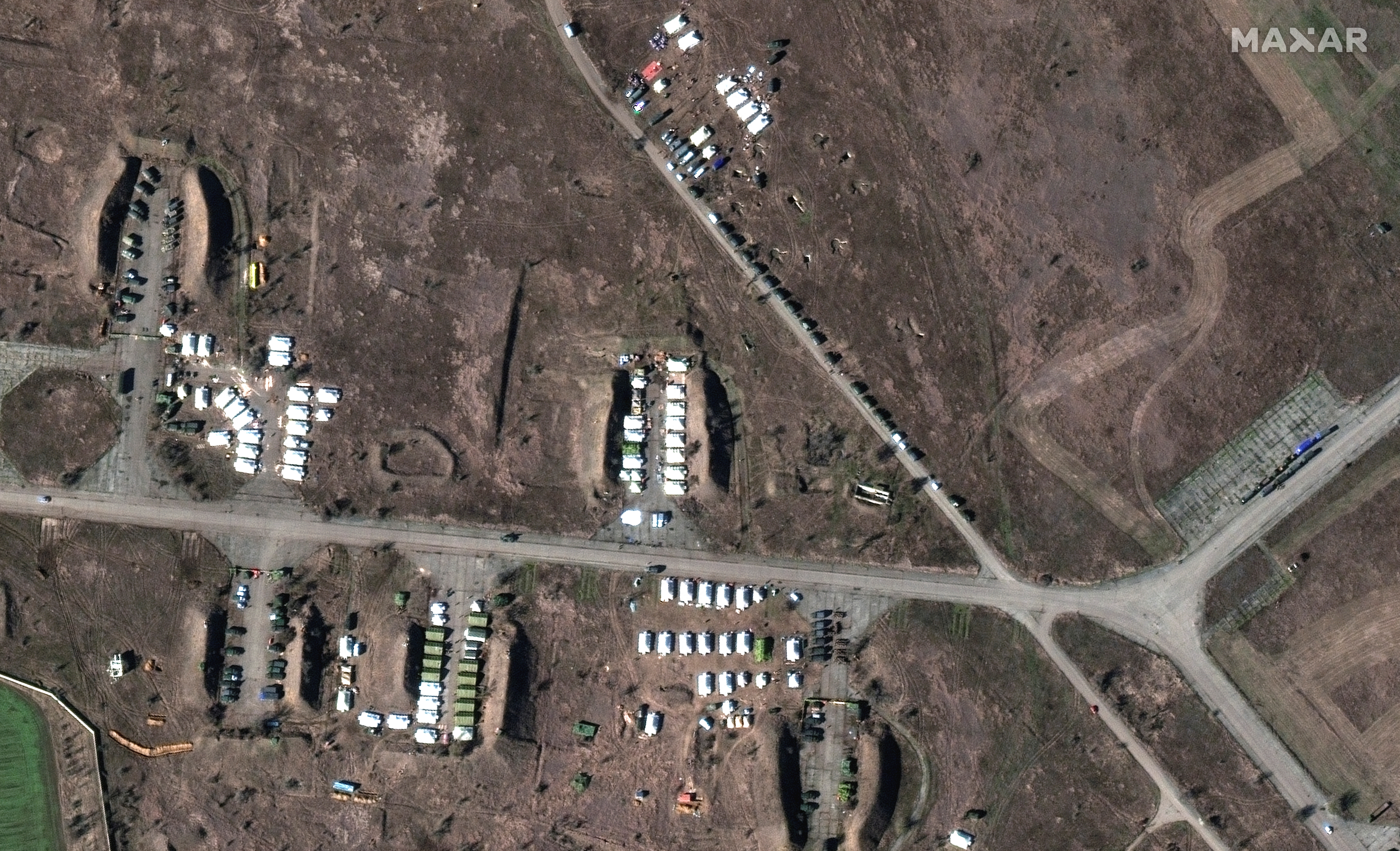 A satellite image shows a tent camp and equipment at the southern end of Oktyabrskoye air base