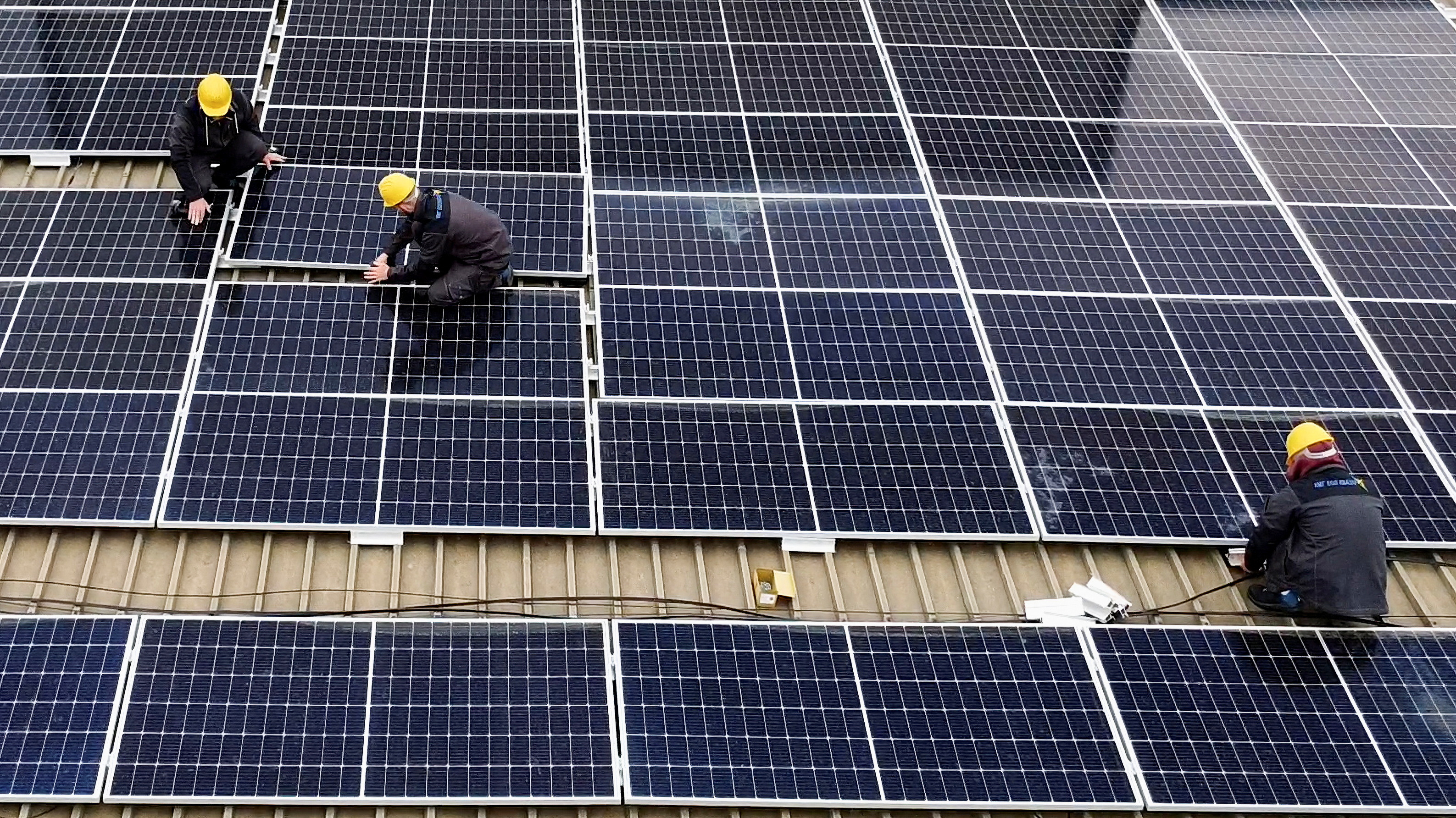 Workers install solar panels on an office building in Skopje