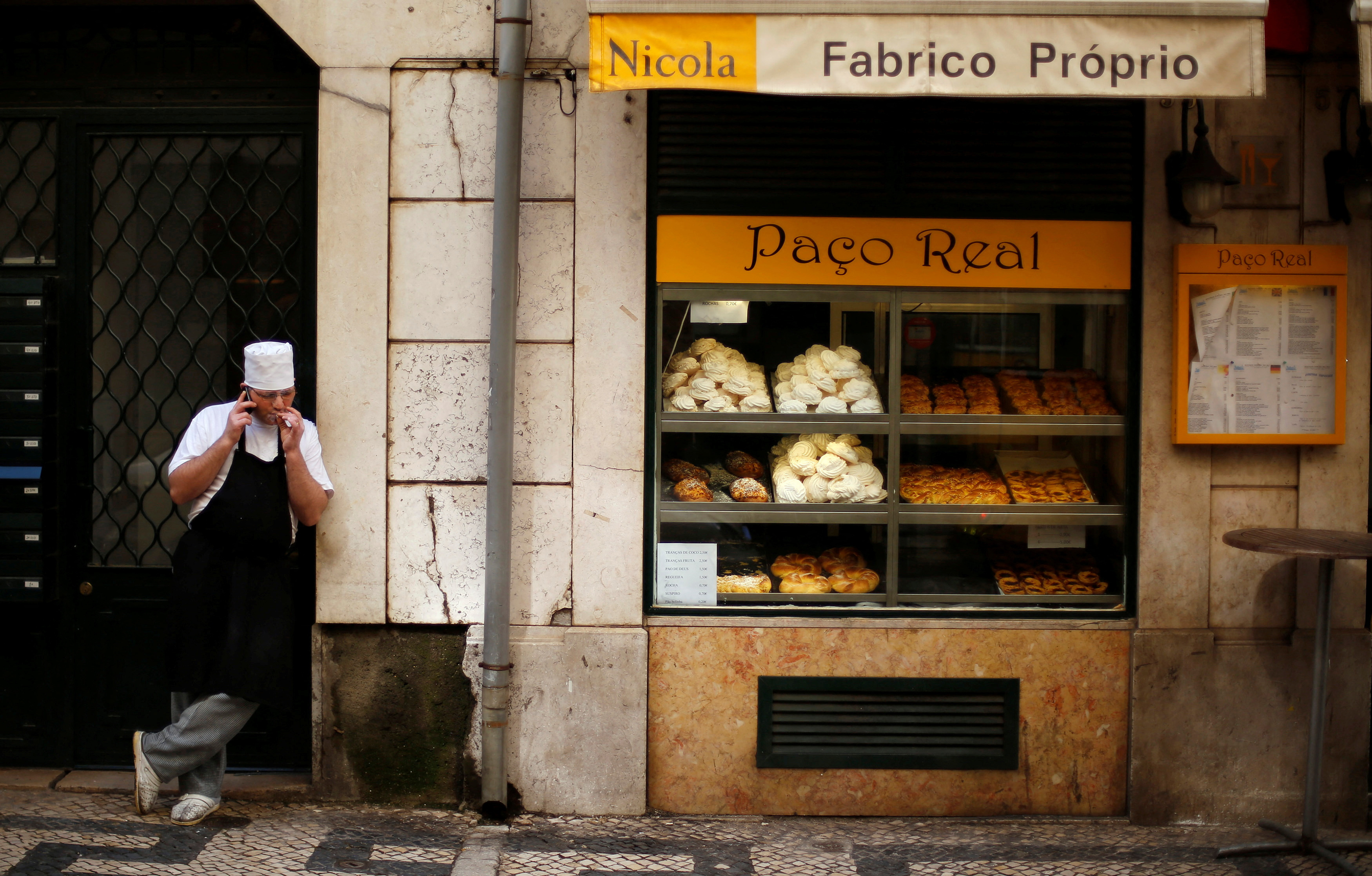 A pastry chef smokes as he talks on the phone in downtown Lisbon
