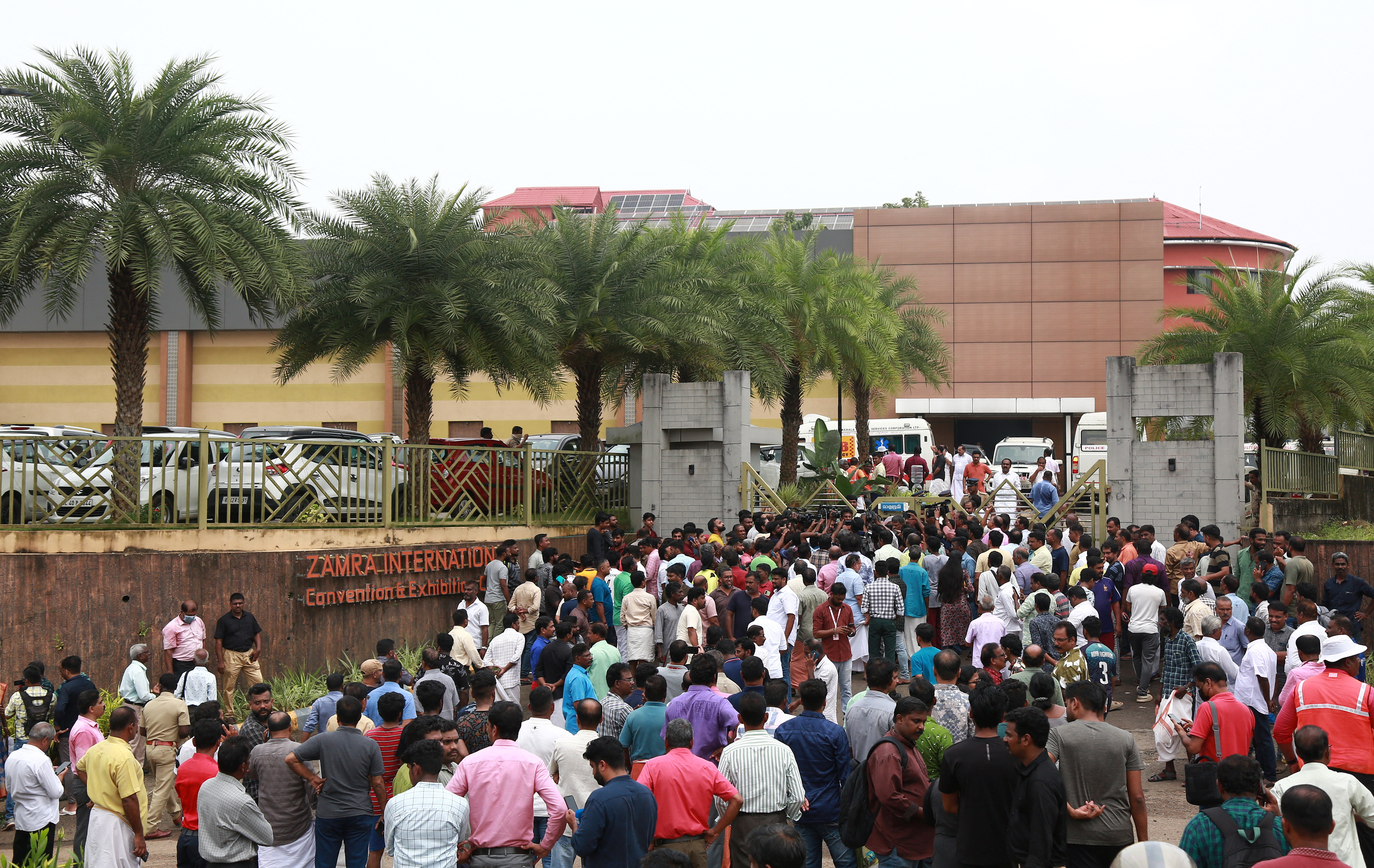 People stand outside a convention centre where multiple blasts occurred during a religious gathering in Kochi
