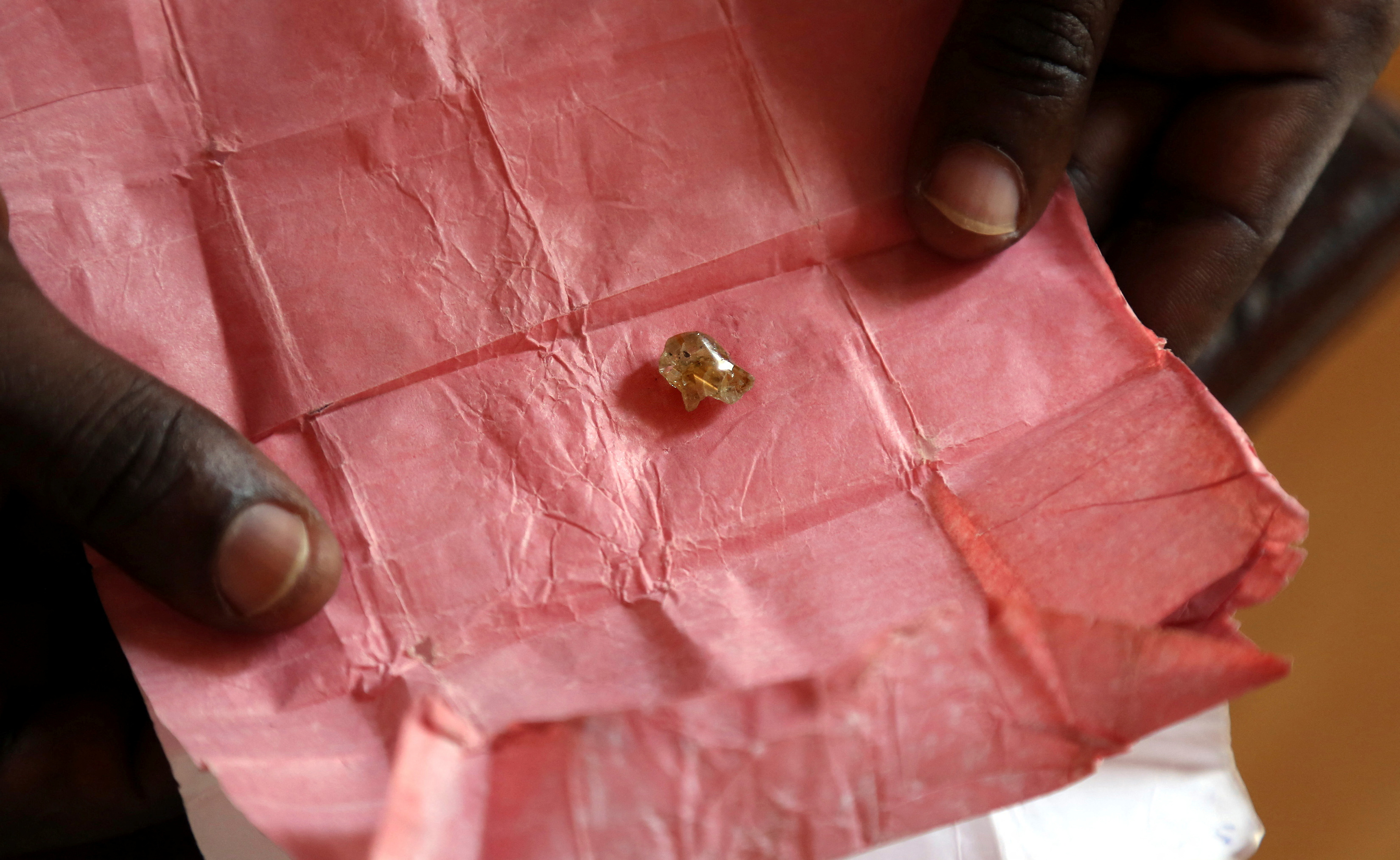 A man displays a rough diamond, from the Boda region, for sale in Bangui