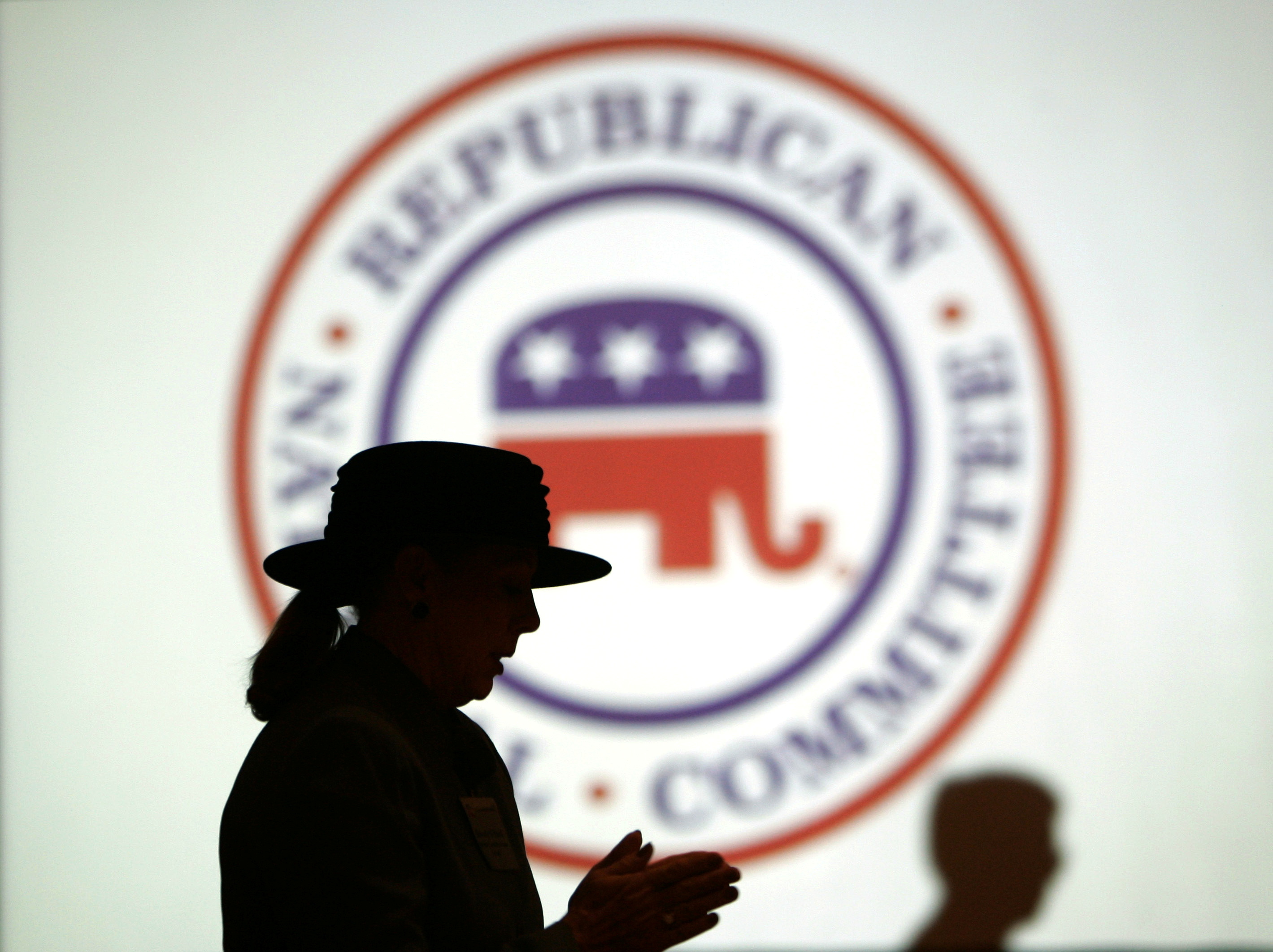 Republican Party members are silhouetted against RNC logo during a meeting in Washington