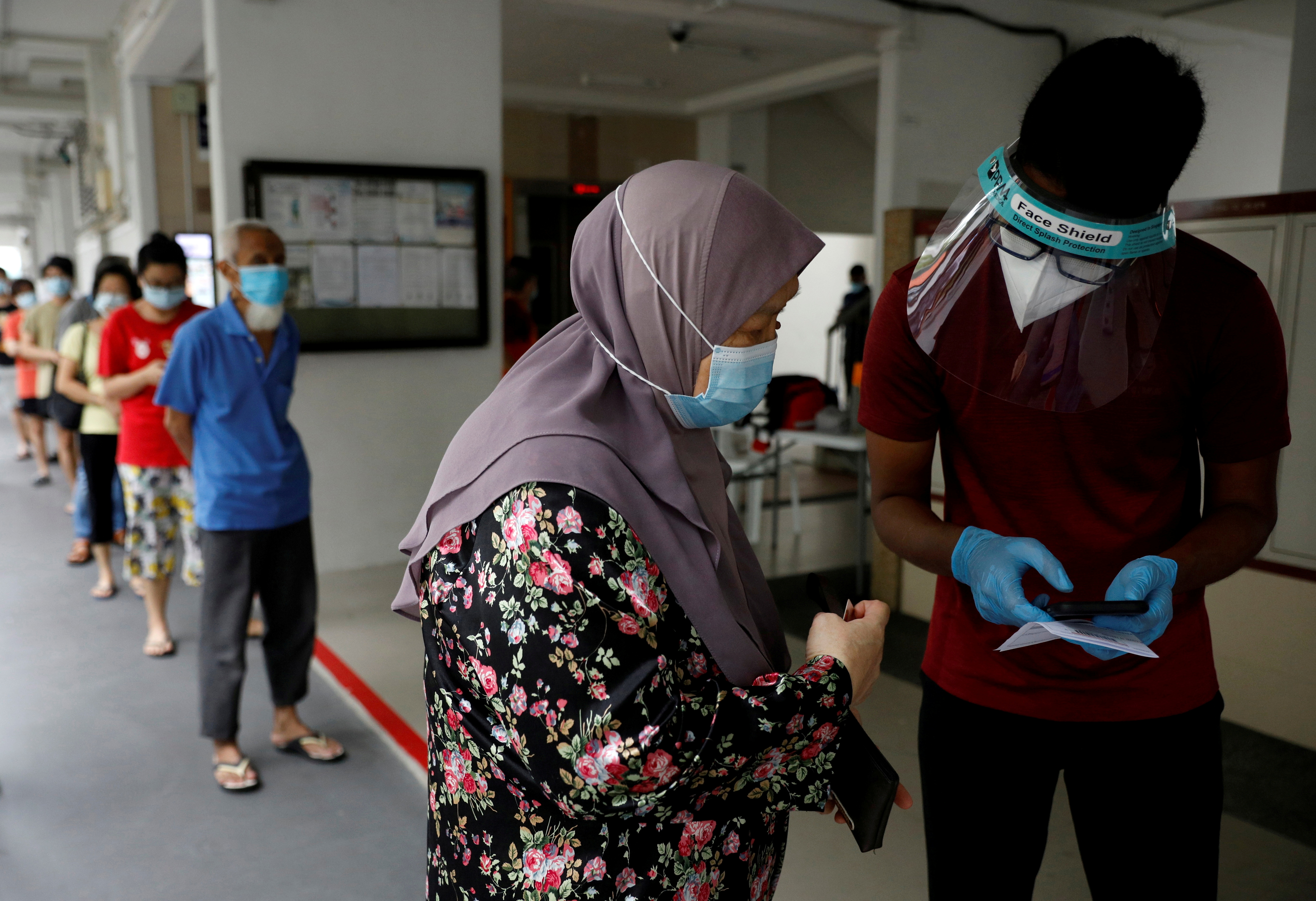 Residents of a public housing estate queue up for their mandatory coronavirus disease (COVID-19) swab tests after some residents were tested positive for the virus, in Singapore