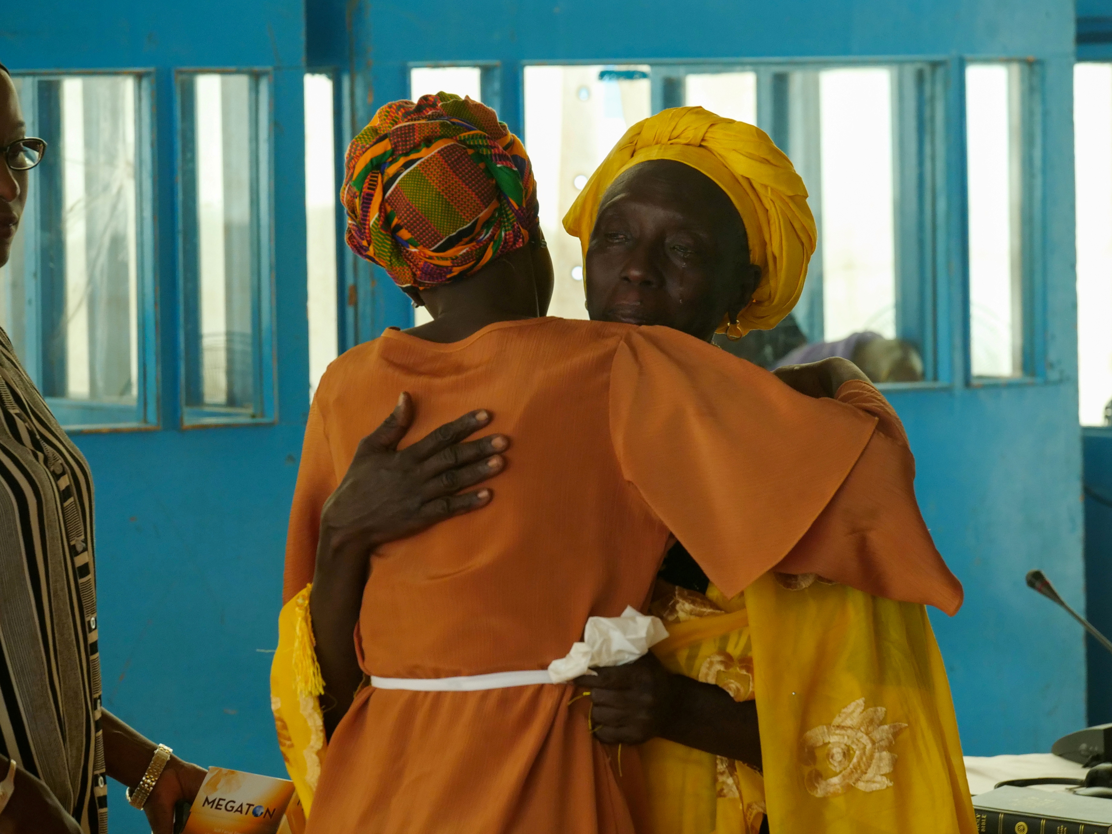Adama Gassama, victim of the Yahya Jammeh era witch hunt, embraces a counsel after hearing at the Truth and Reconciliation and Repsarations Commission in Eassau,