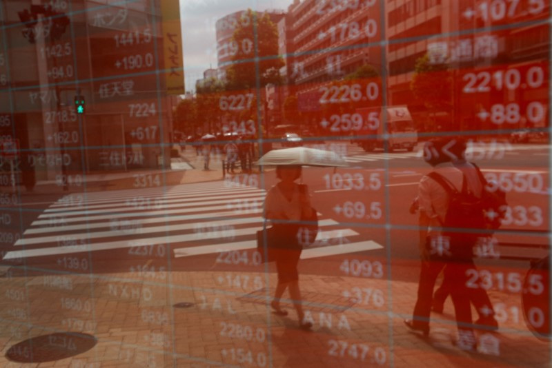 A woman is reflected on an electronic stock quotation board outside a brokerage in Tokyo