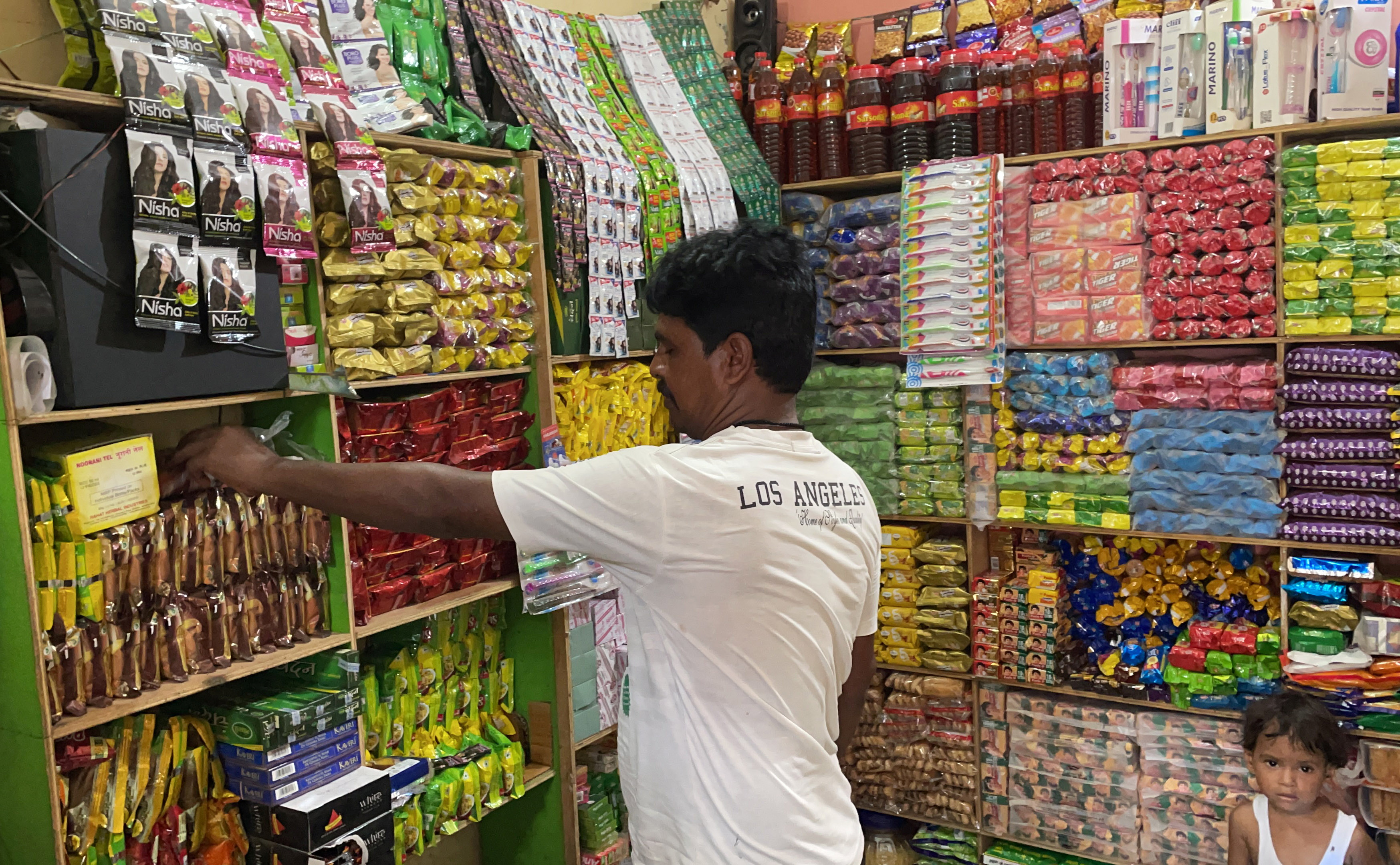 Gosh Mohammed, a retail shop owner, arranges snacks inside his shop in Dihwa
