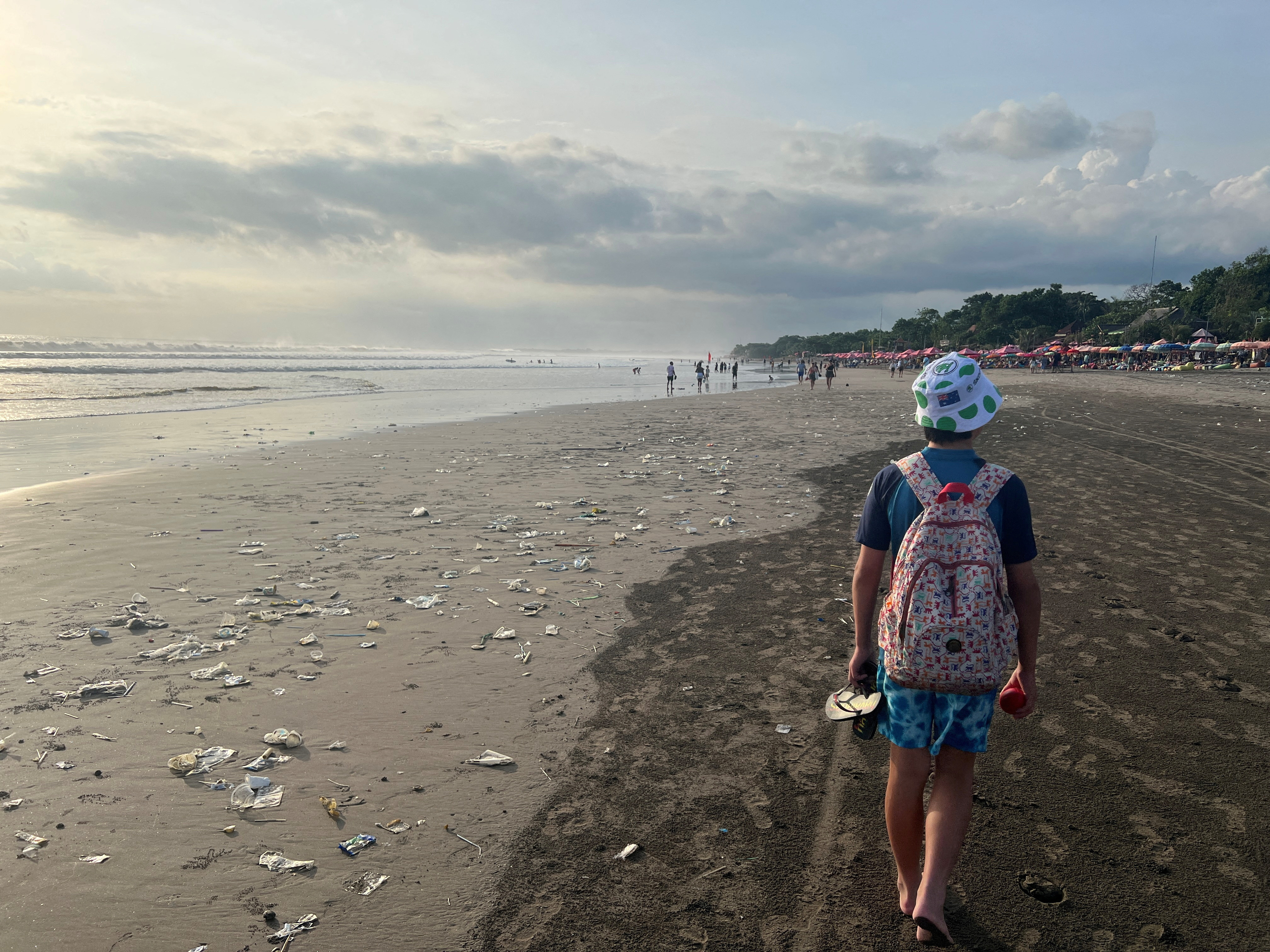 A boy walks on a beach polluted by plastic trash in Bali