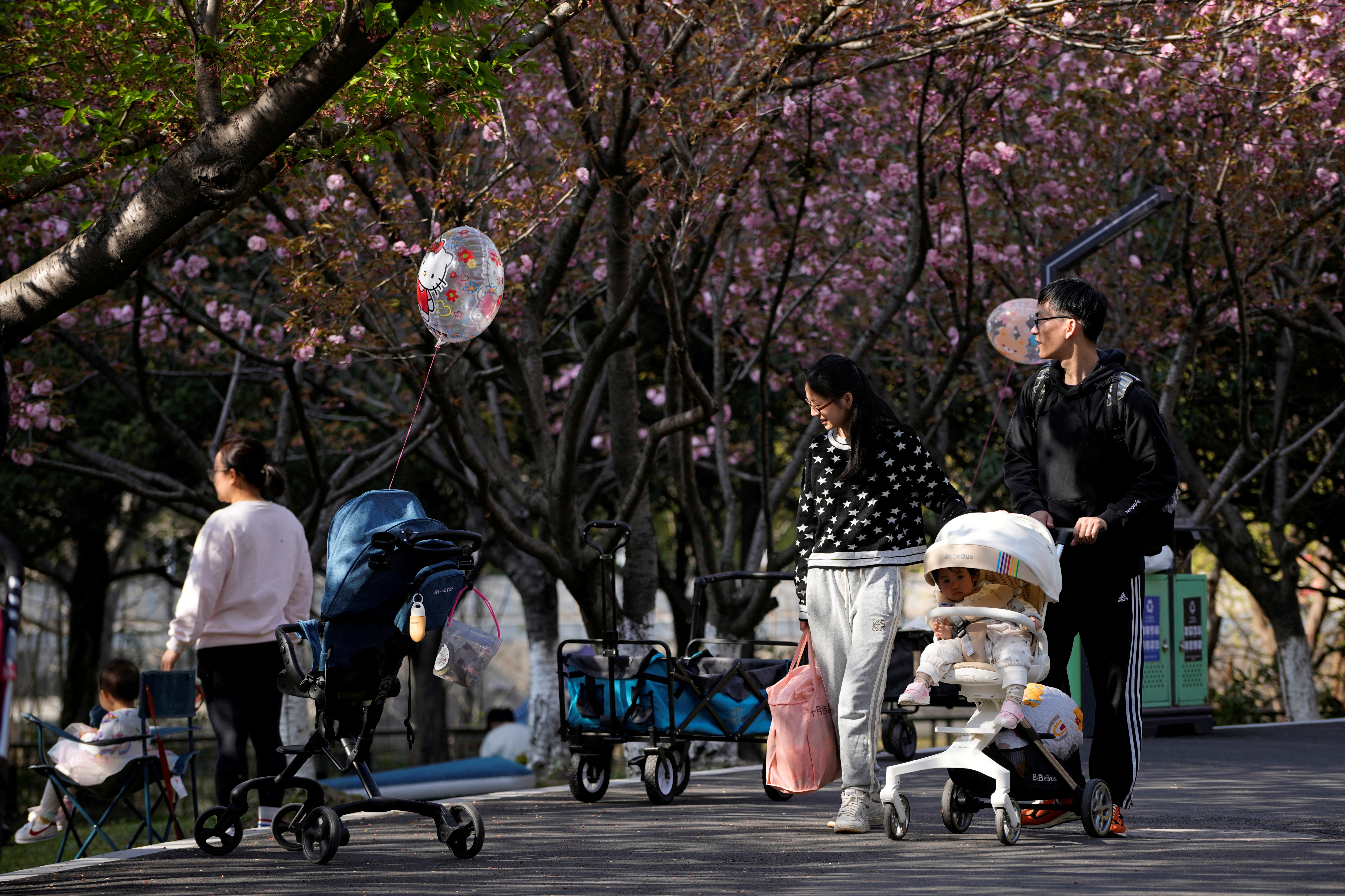 A parents pushes a stroller with a baby in a park in Shanghai