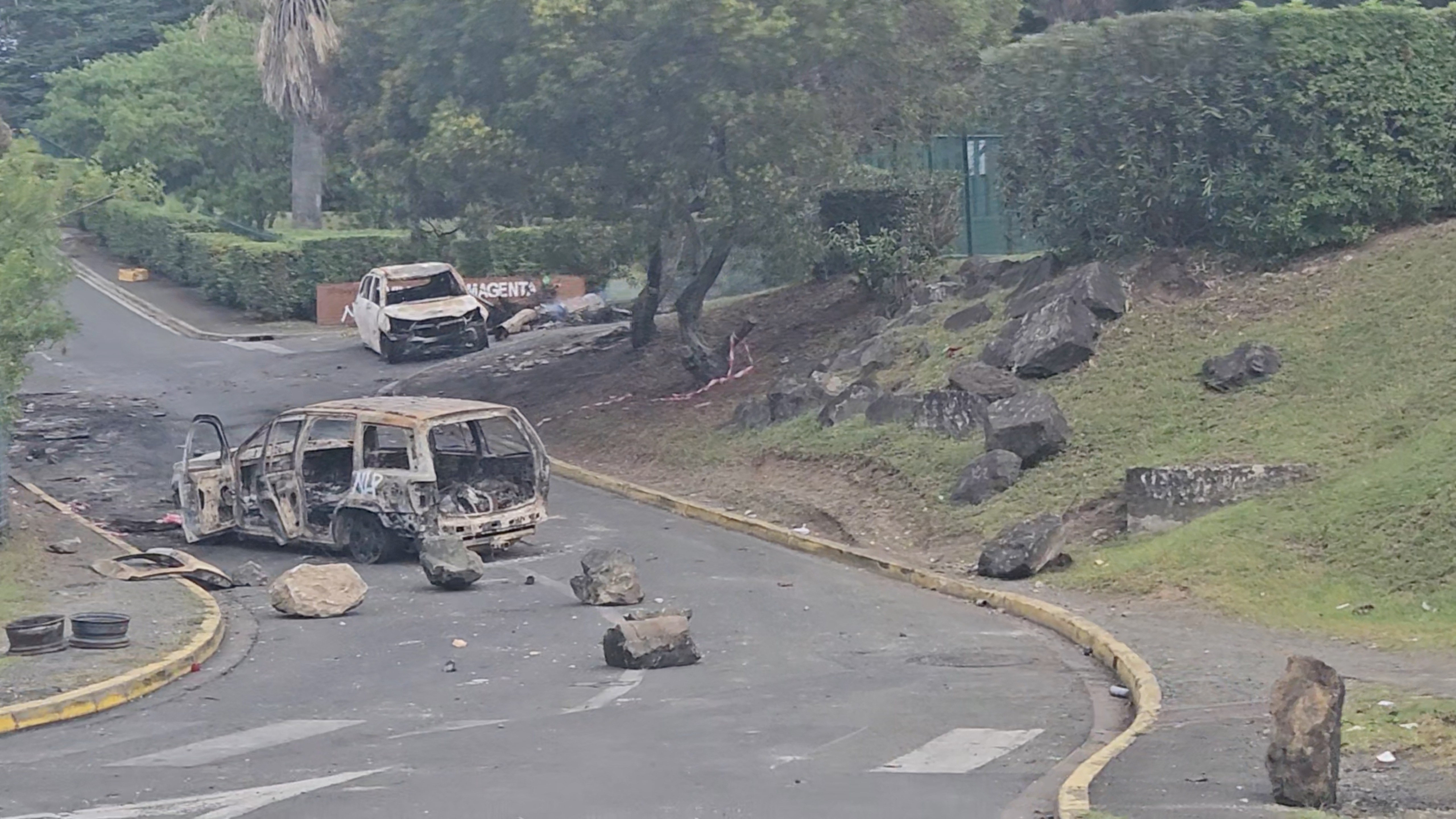 A view of burnt cars on a road in Noumea