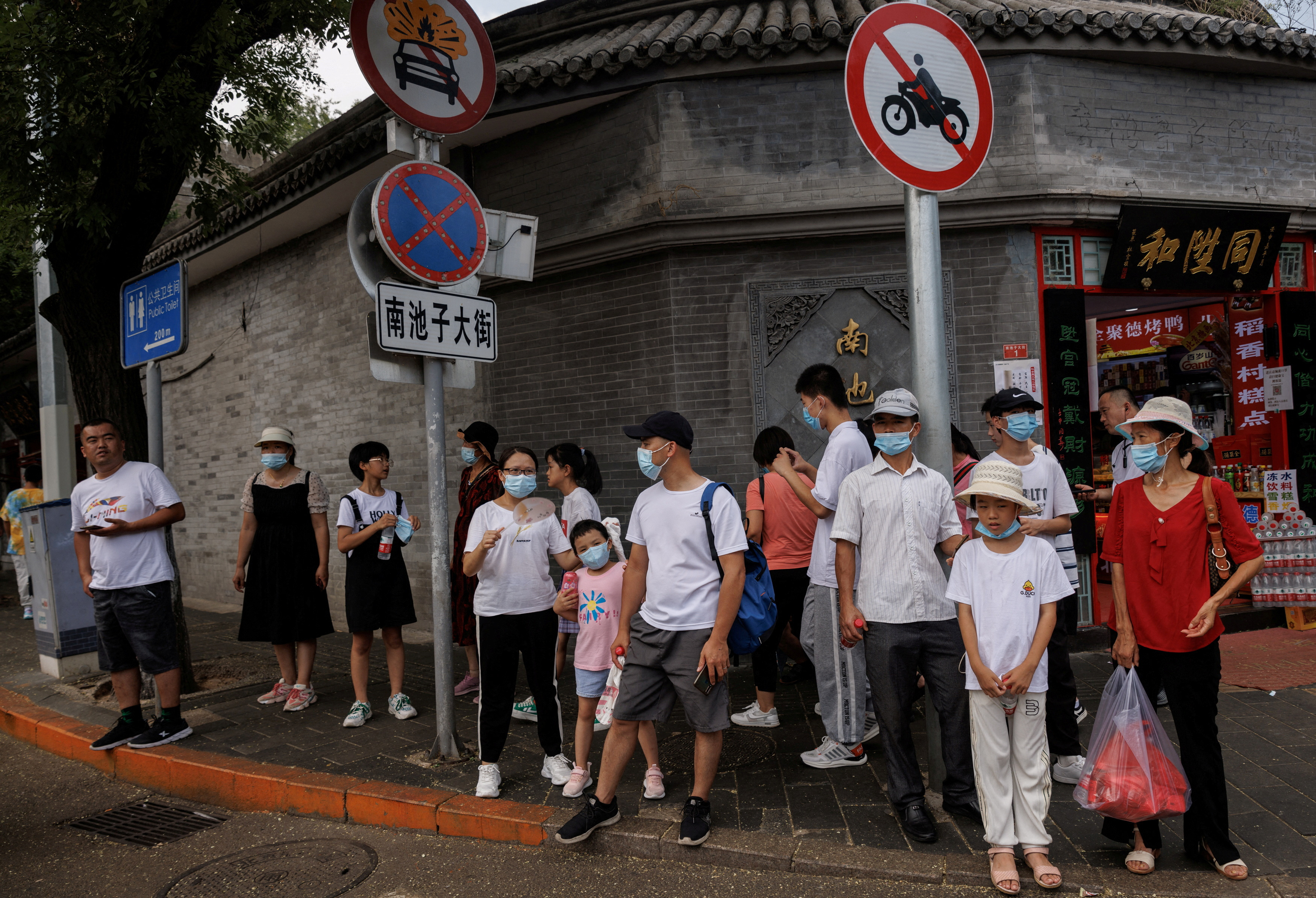 People wear face masks as they stand in a street following a coronavirus disease (COVID-19) outbreak, in Beijing