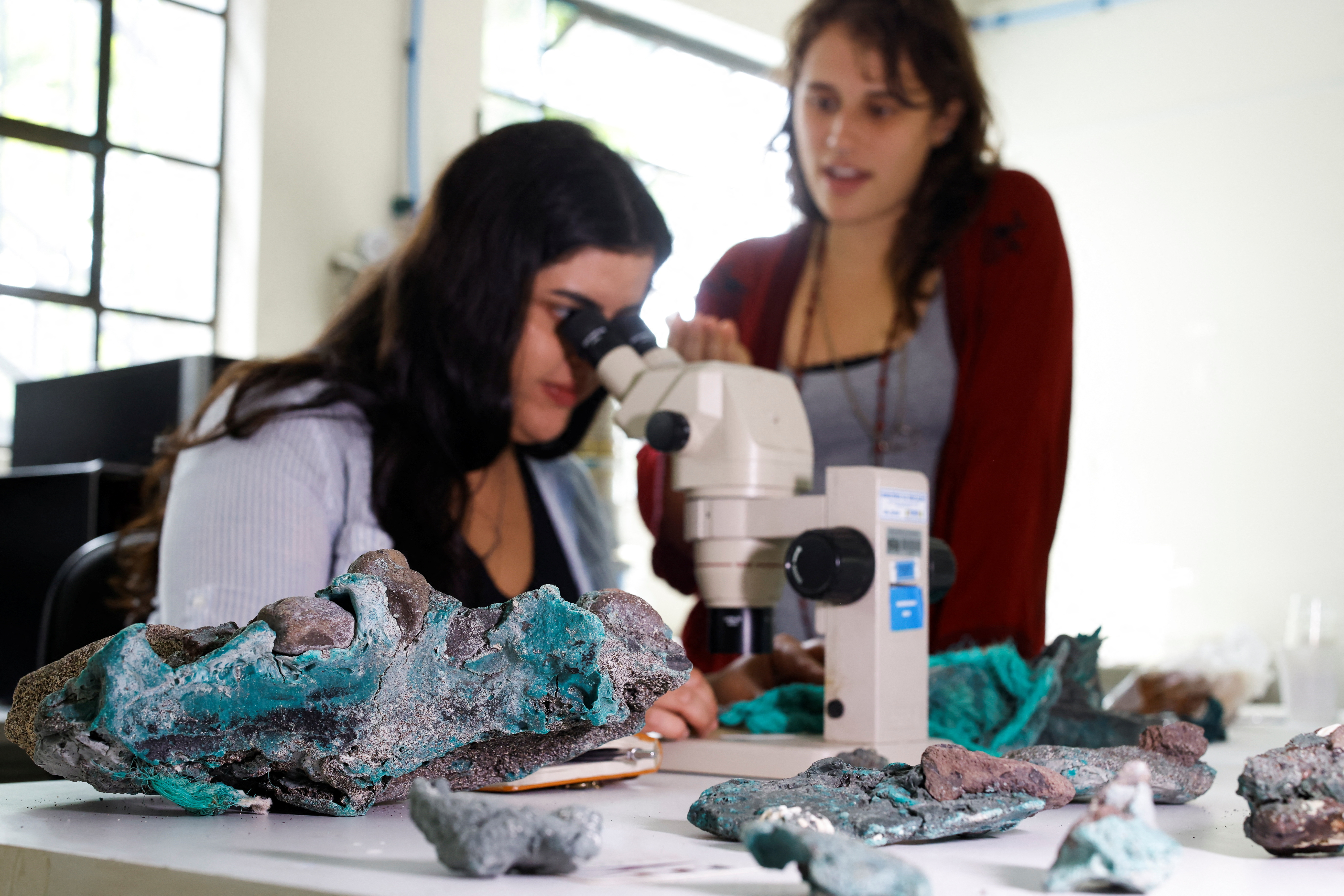 Researcher Fernanda Avelar Santos looks through a microscope at "plastic rocks" found on Trindade Island, at the laboratory of the Federal University of Parana, in Curitiba