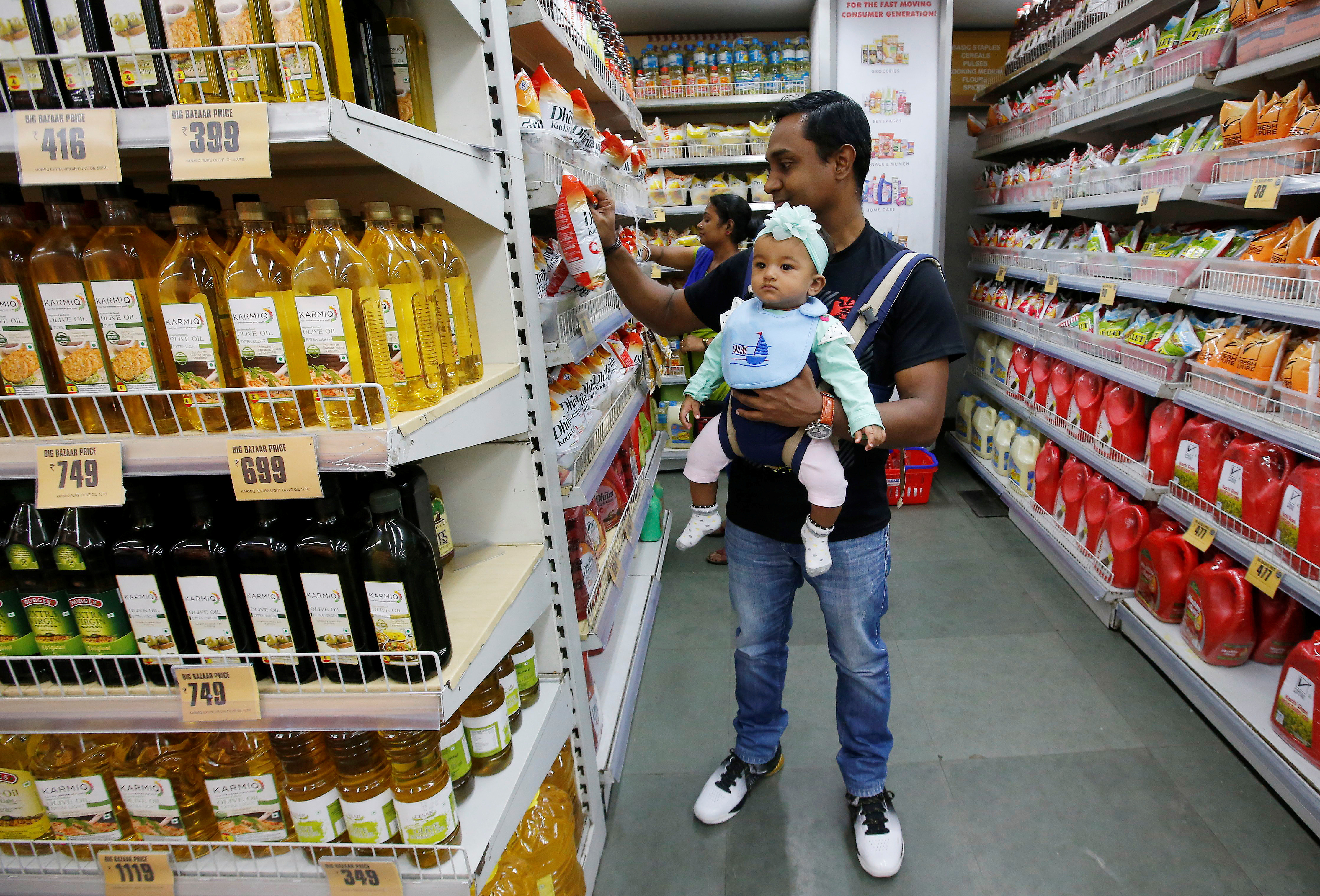 A customer carries his daughter as he buys goods at a store inside a shopping mall in Kolkata