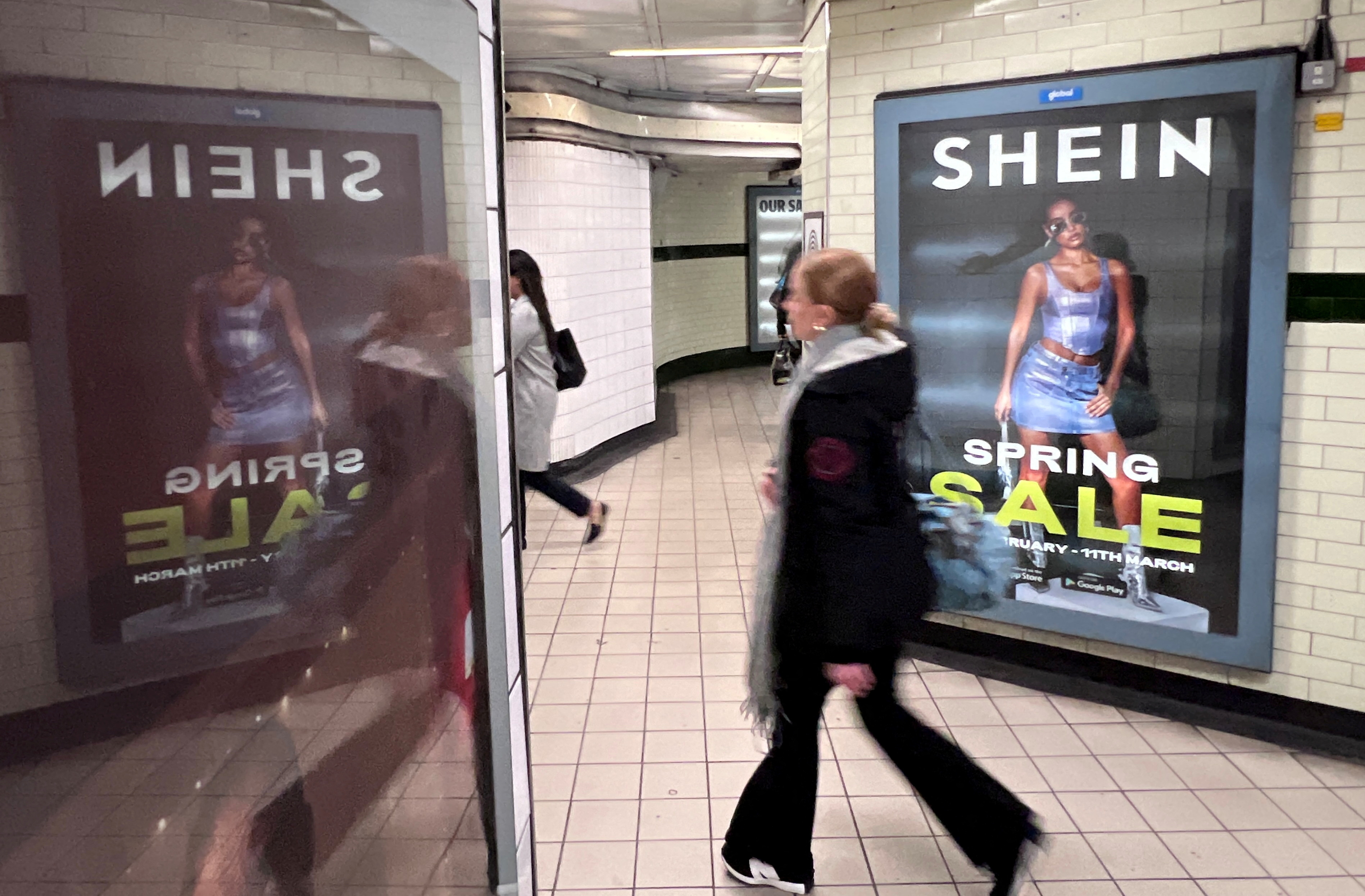 People walk past an advertisement for Shein