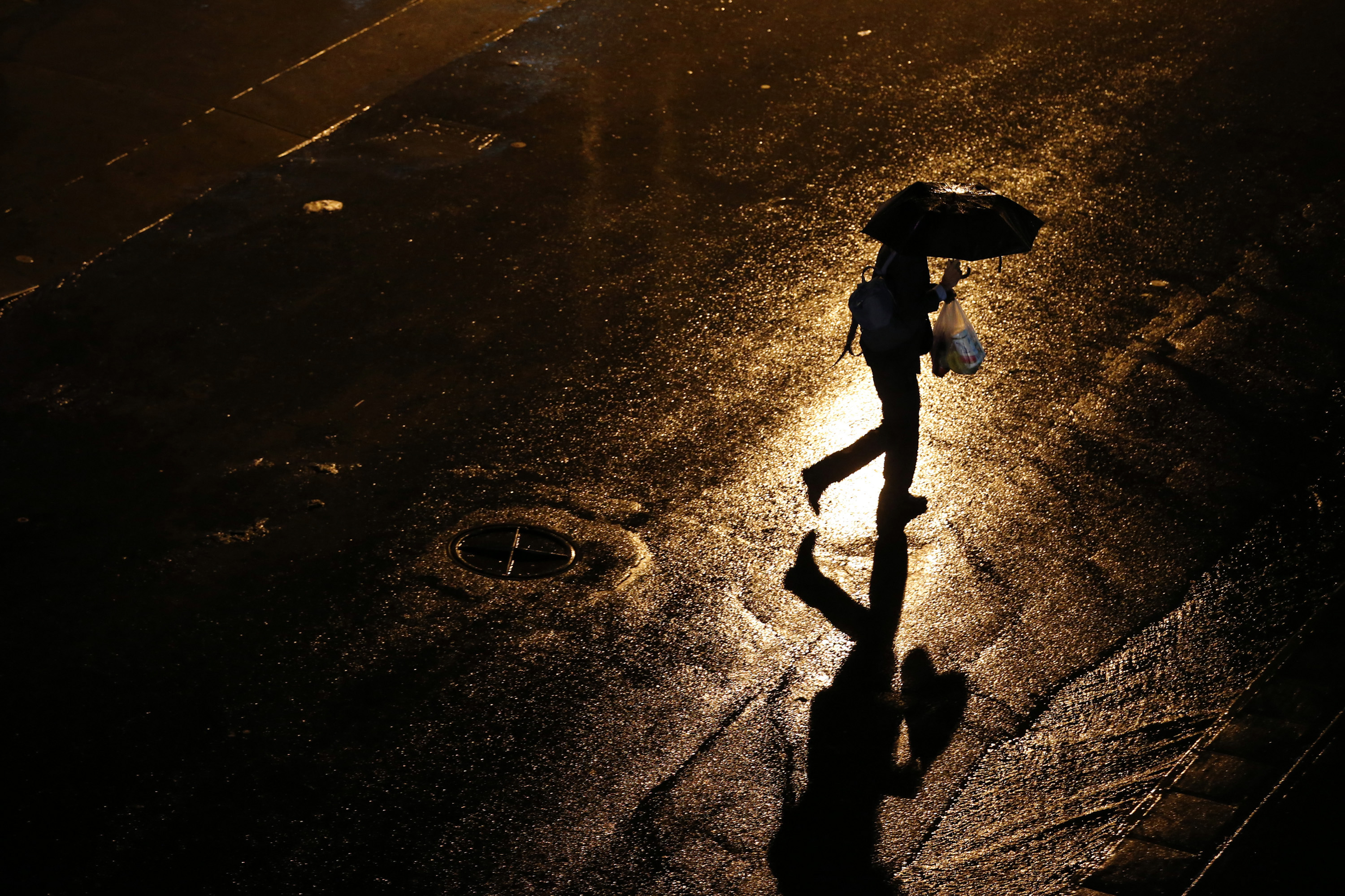 A man crosses a street under the rain in Caracas