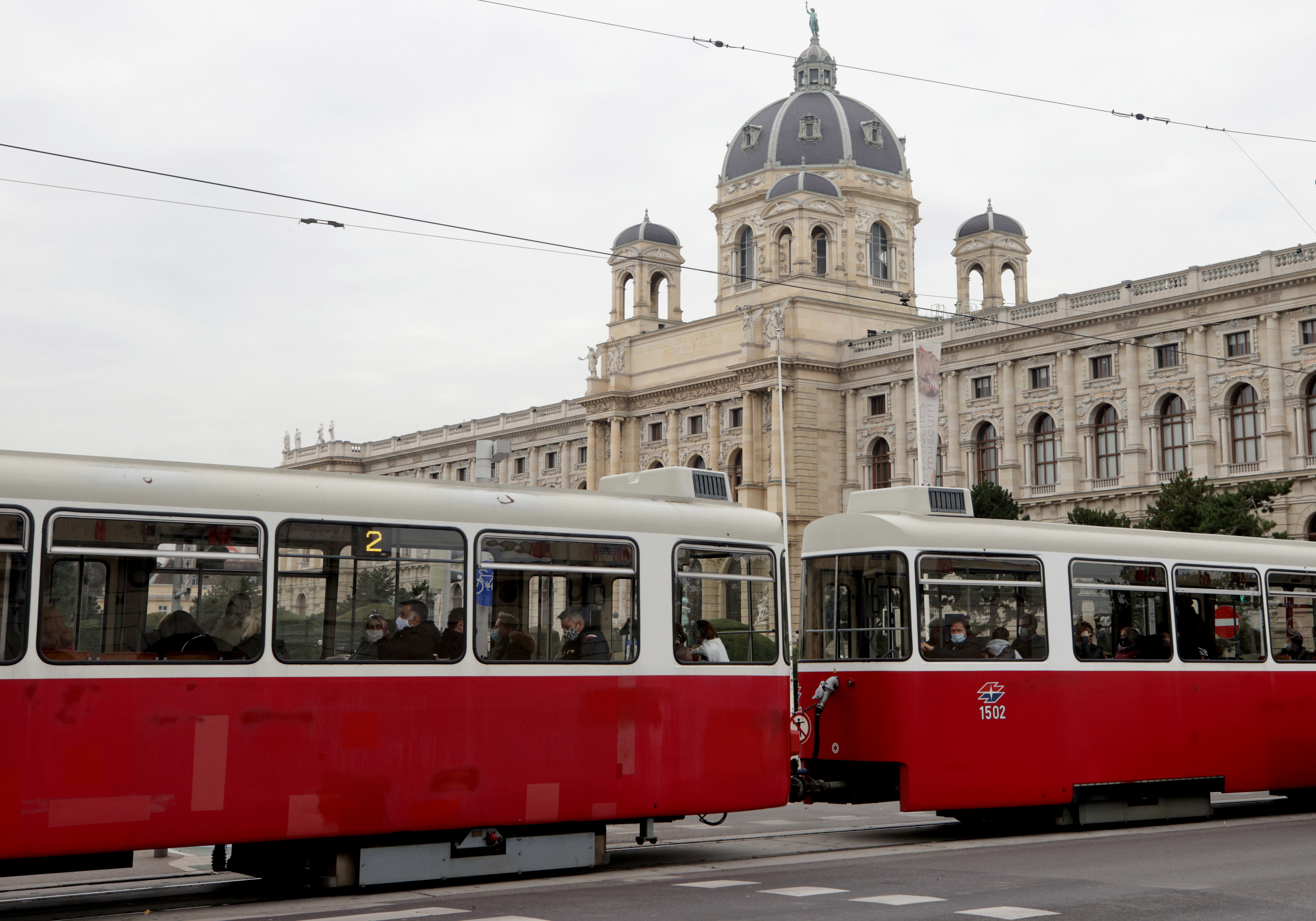 People ride a tram as it passes the Natural History Museum in Vienna