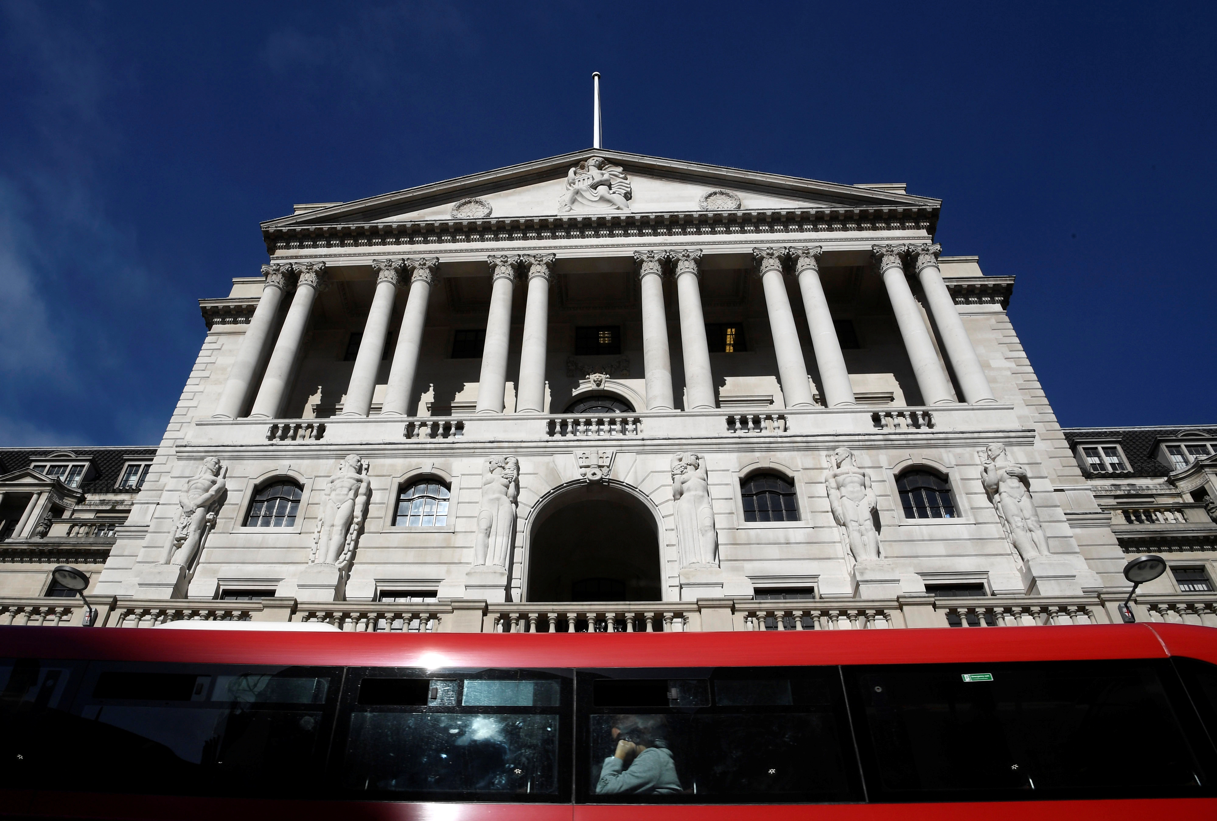 People travel on a bus as it passes the Bank of England in the City of London