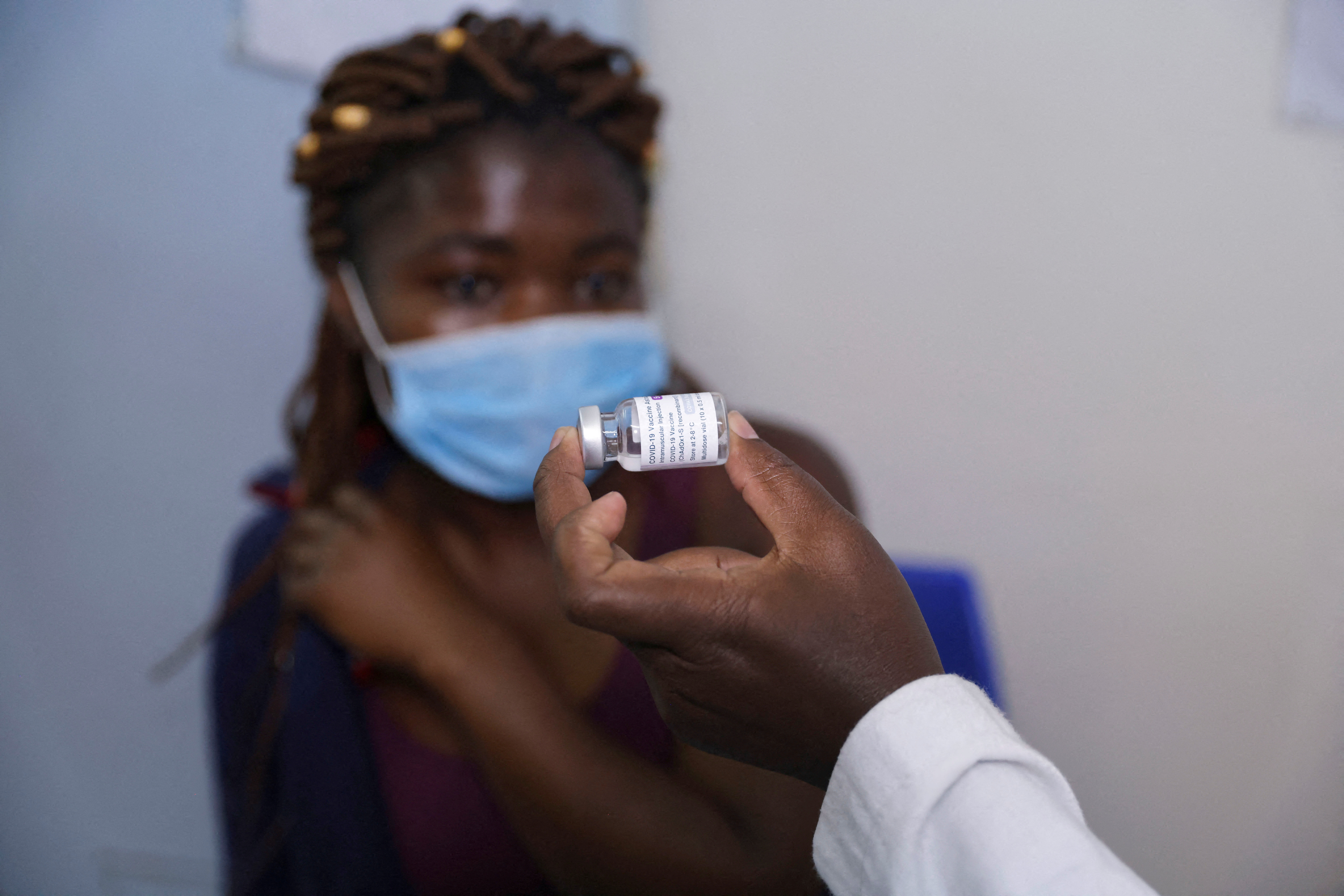 A health worker shows a woman a vial containing a COVID-19 vaccine before administering it to her, at the Penda health center in Nairobi