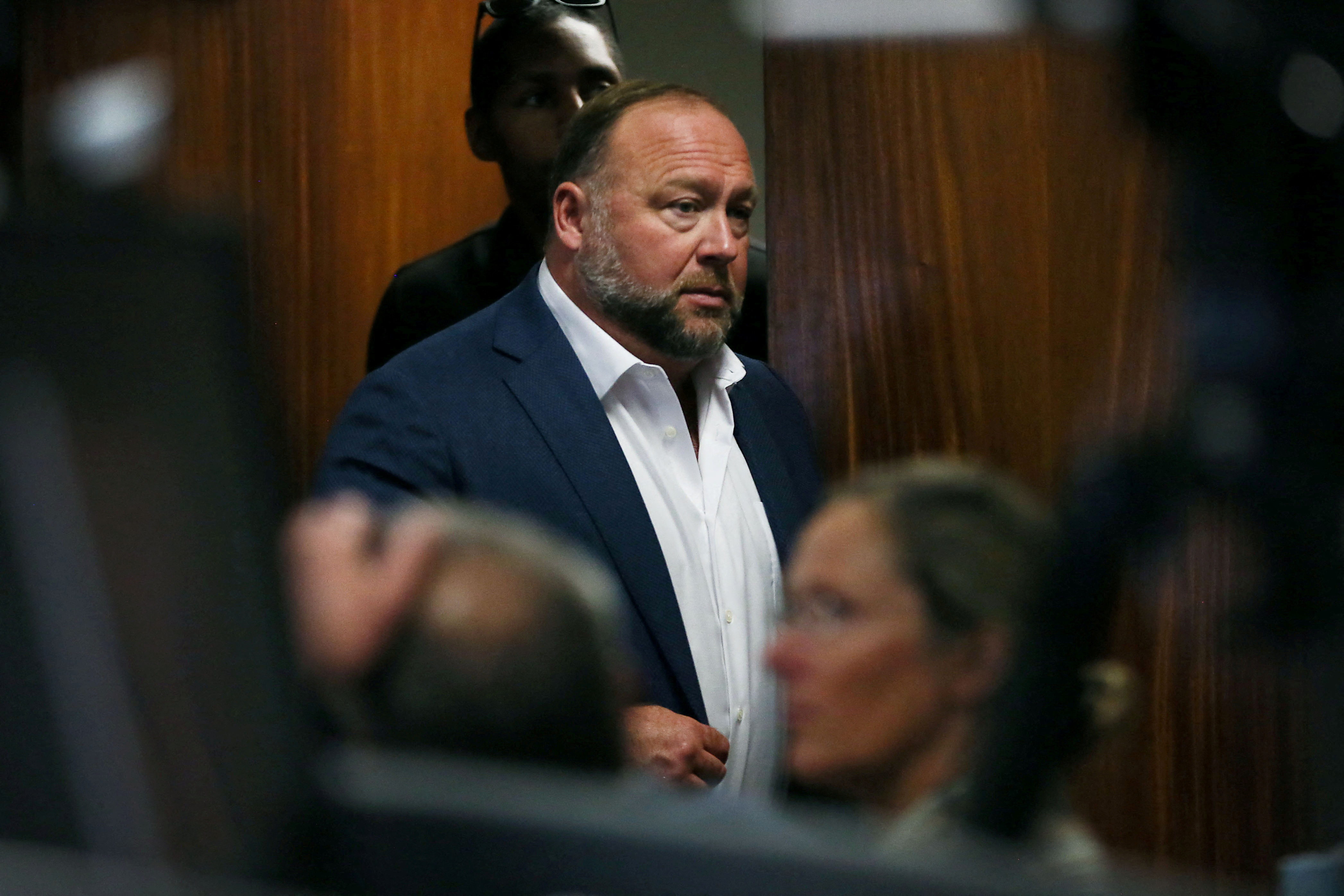 Alex Jones walks into the courtroom in front of parents of 6-year-old Sand Hook shooting victim Jesse Lewis in Austin