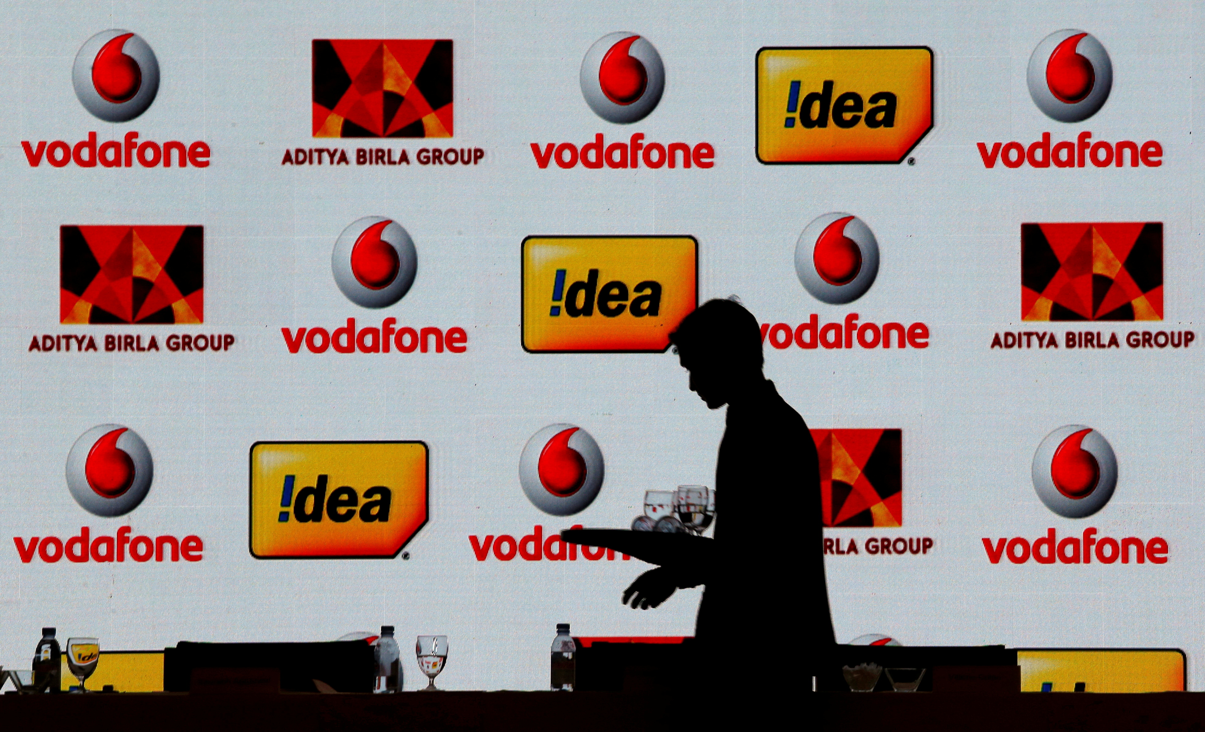A hotel employee clears a table after Vodafone Group and Idea Cellular news conference in Mumbai