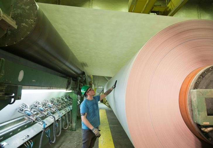 A winder crewman inspects the Jumbo roll as it prepares to unwind the newspaper into rolls at Resolute Forest Products in Gatineau