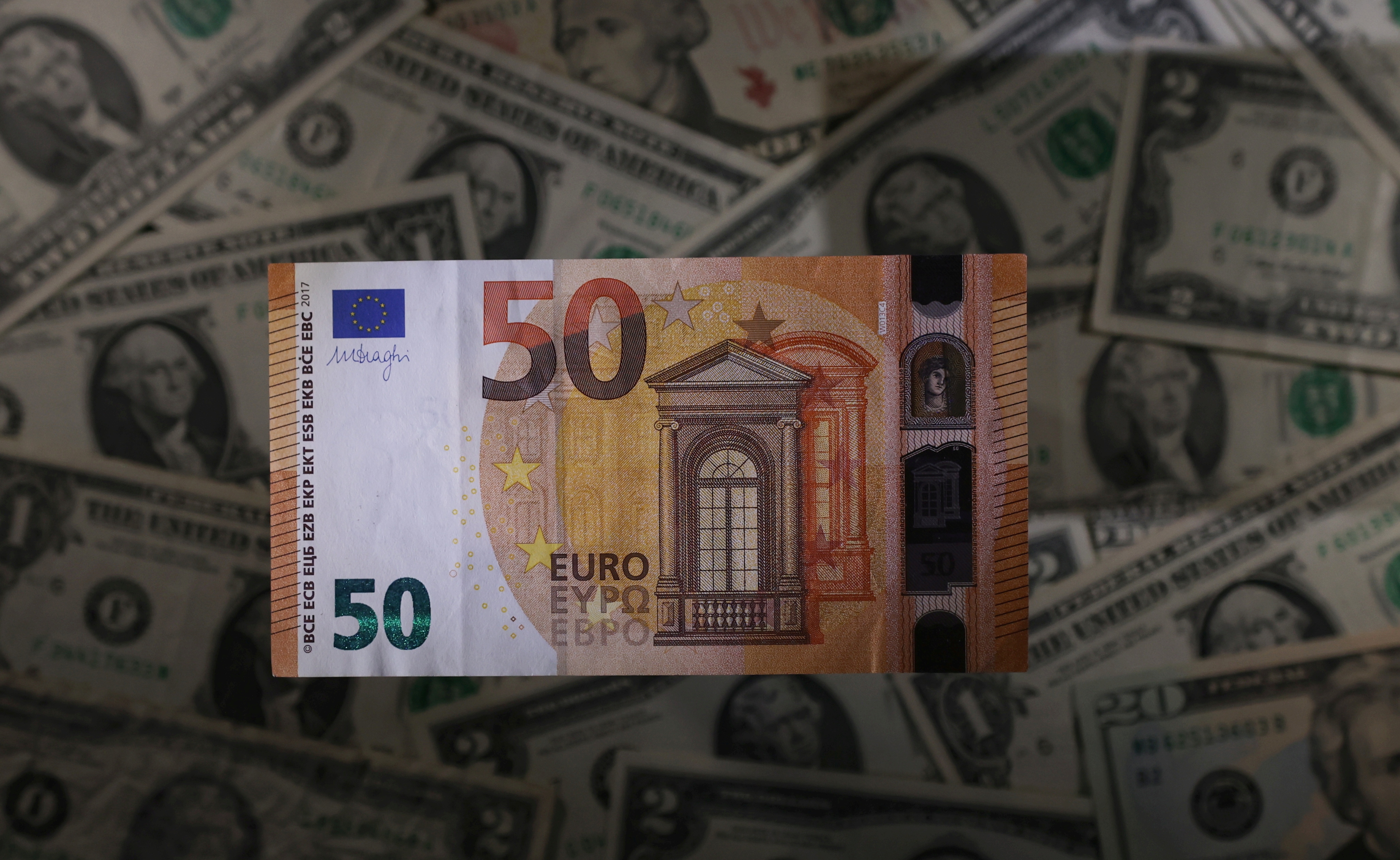 Euro banknote is seen placed on U.S. Dollar banknotes in this illustration