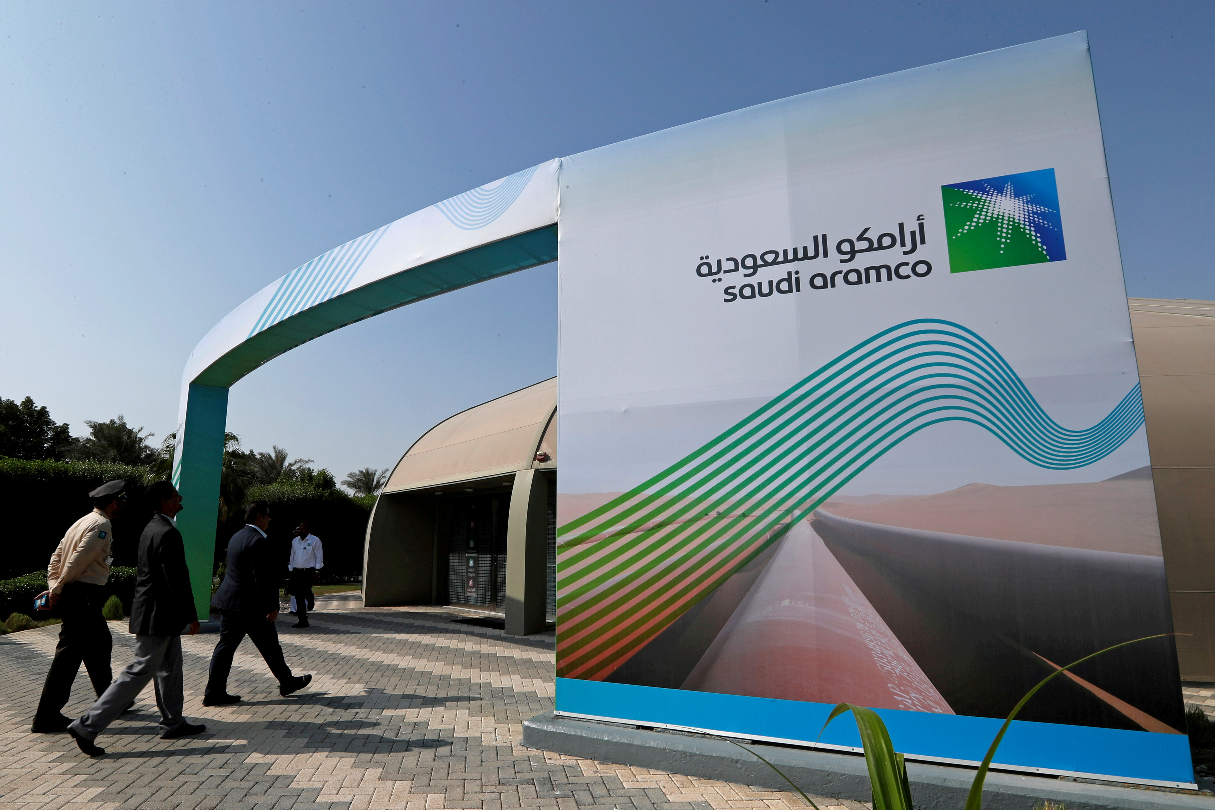 Logo of Aramco is seen as security personnel walk before the start of a press conference by Aramco at the Plaza Conference Center in Dhahran