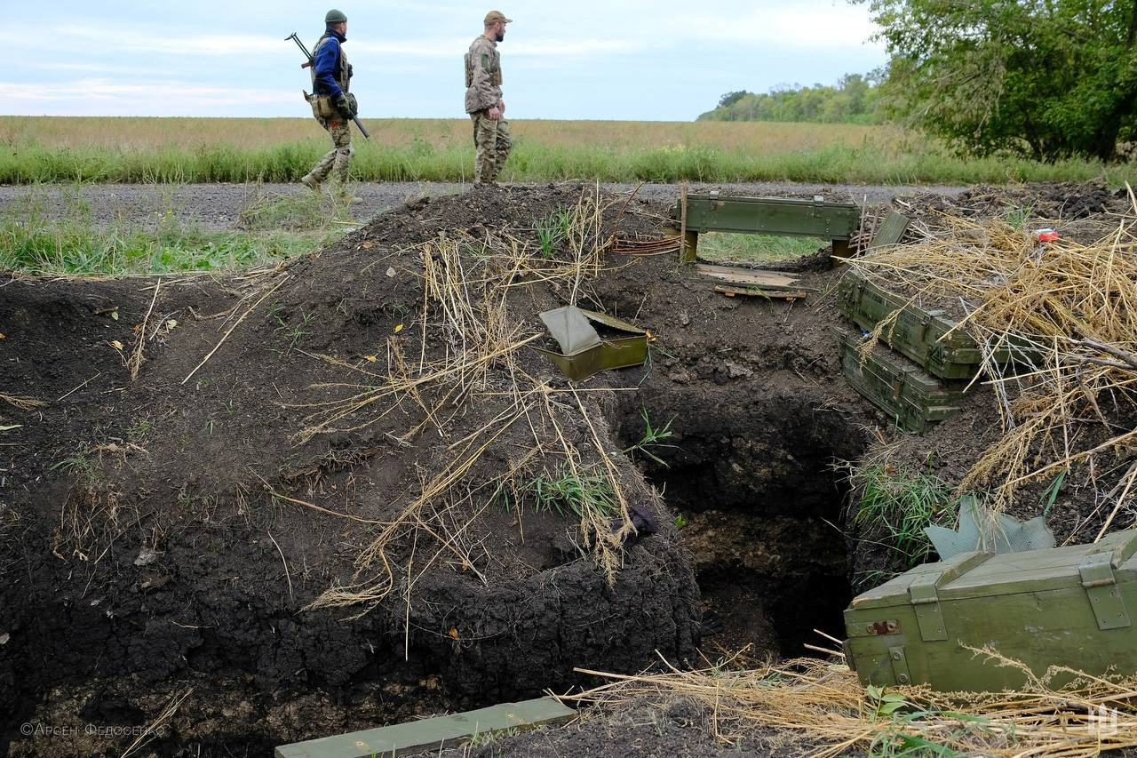 Ukrainian service members walk past a former position of Russian soldiers captured during a counteroffensive operation in Kharkiv region